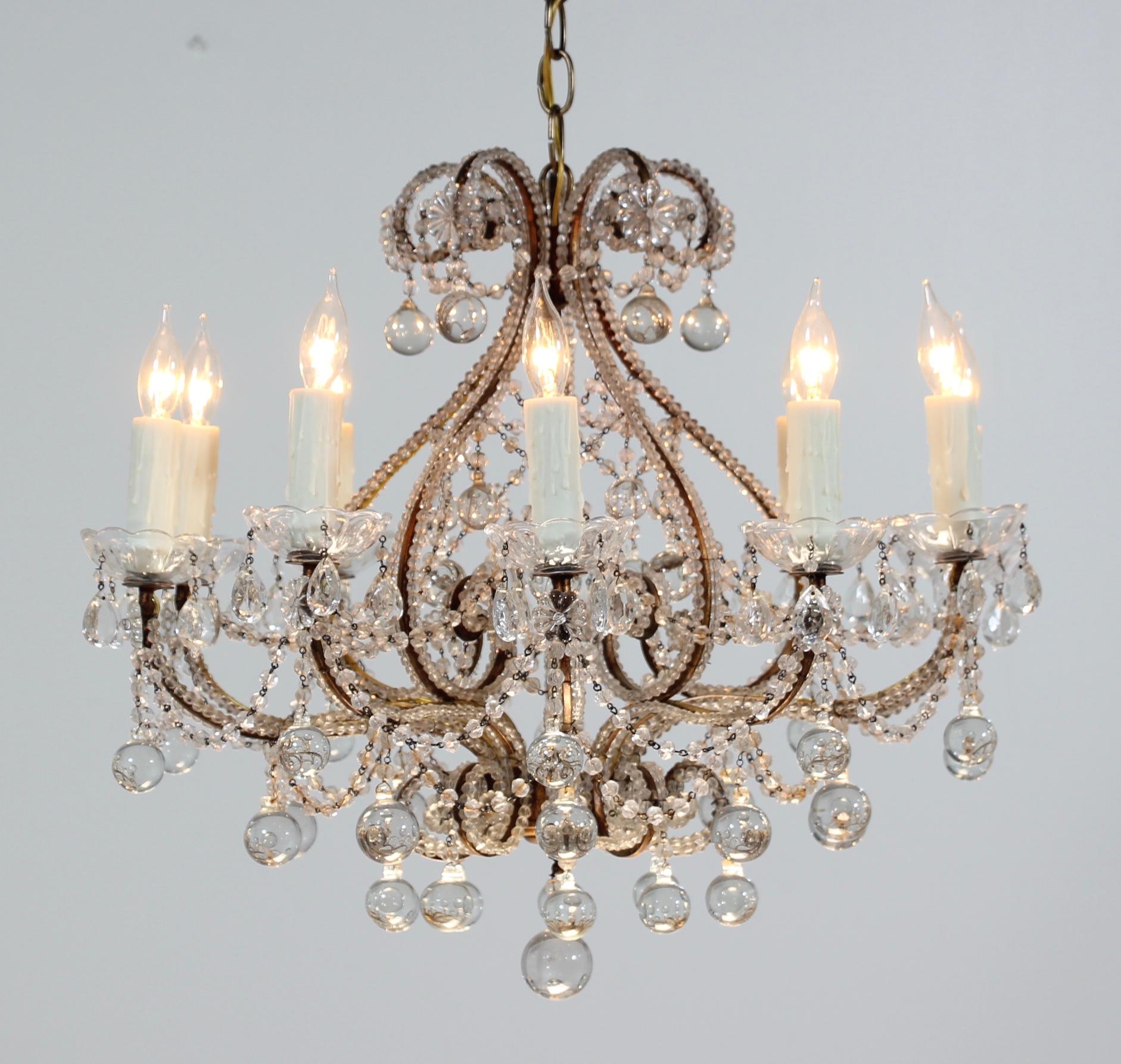      Beautiful, 1940s Italian gilt iron and crystal beaded chandelier. The chandelier consists of a curvaceous gilded iron frame which has been hand beaded with “English cut” beads. Glass ball drops in a variety of sizes complete the chandelier’s