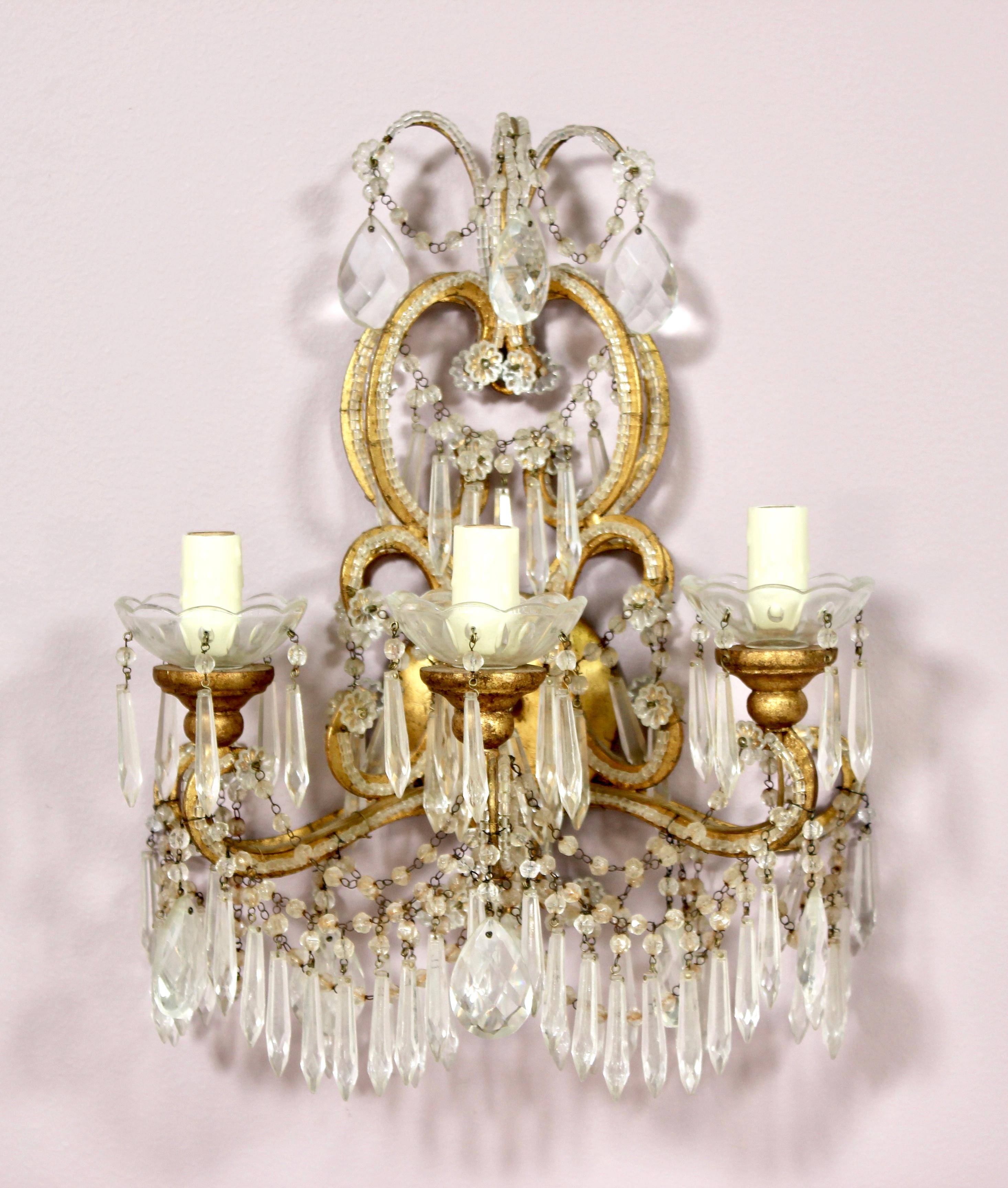 Beautiful pair of 1920s Italian crystal beaded sconces featuring gilt iron frames embellished with crystal beads, swags and prisms. Original wiring is in working condition. Each sconce requires two candelabra base bulbs. New bee wax candle sleeves.