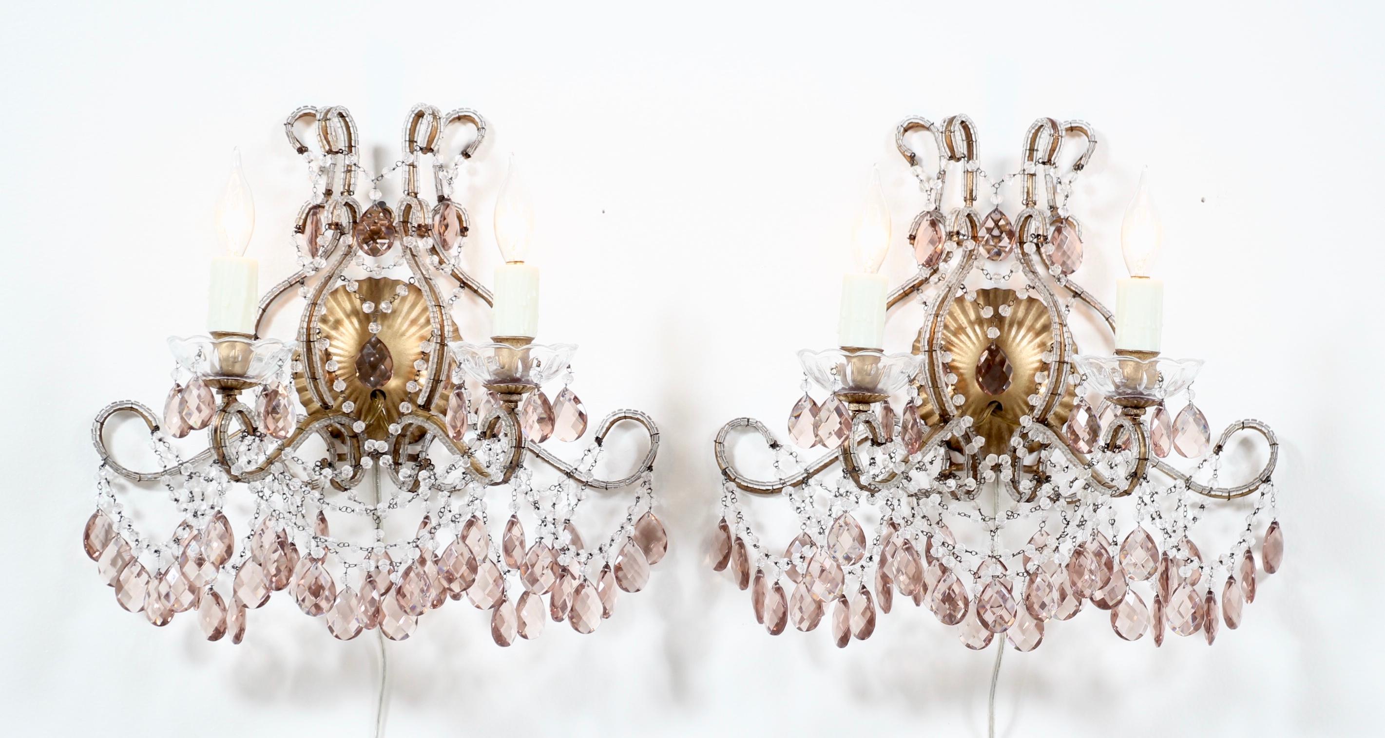      A gorgeous pair of Italian gilt-iron and crystal beaded sconces with light amethyst prisms. These beauties consist of gilded iron frames which were hand beaded with “macaroni” style beads, an abundance of English cut bead garlands and beautiful