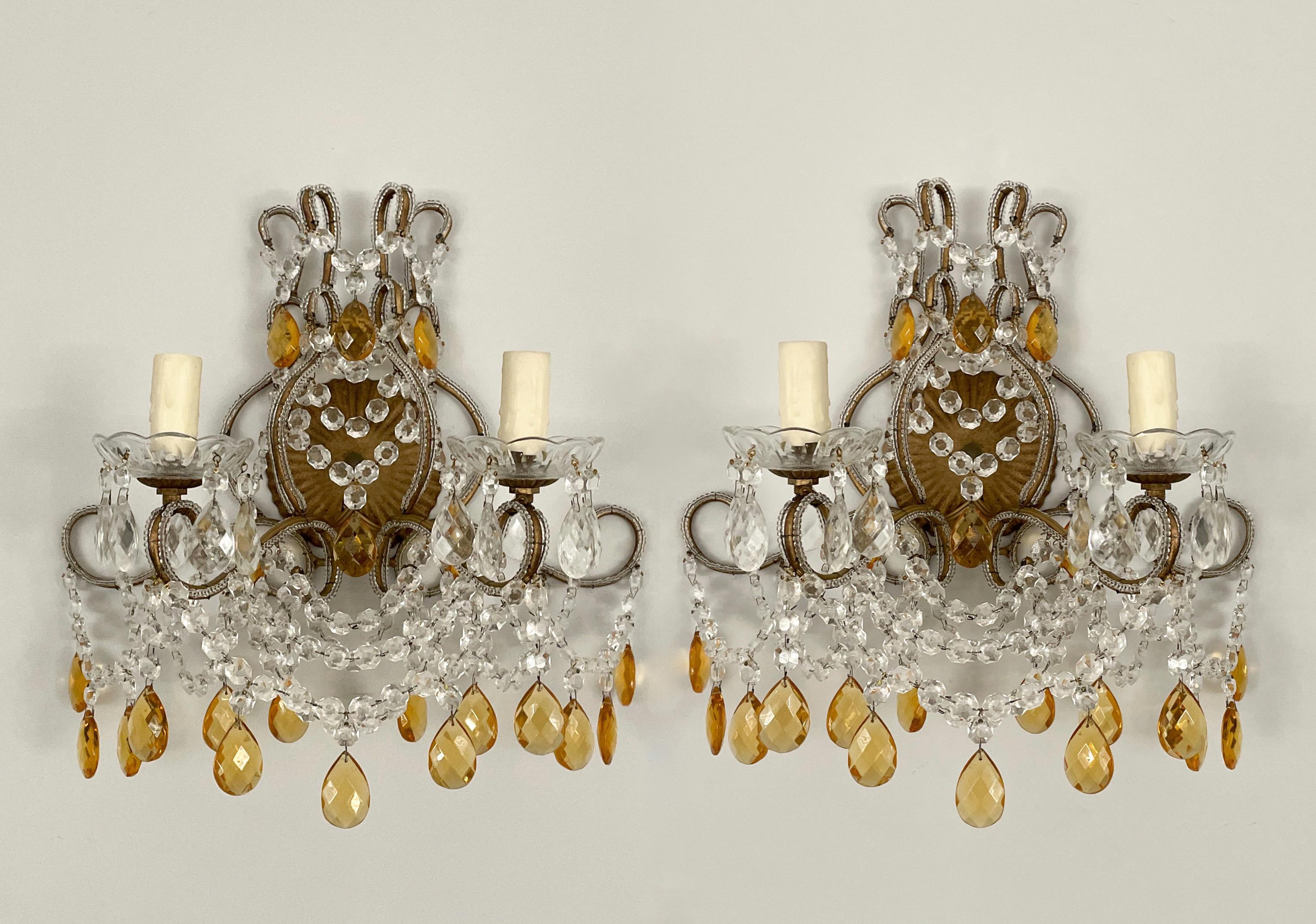 Sehr hübsches Paar italienischer Wandleuchter mit Perlen aus den 1960er Jahren.

Die Leuchter bestehen aus einem vergoldeten, geschwungenen Eisenrahmen mit klaren Kristallperlen und facettierten Prismen aus bernsteinfarbenem Glas. Die Farbe der