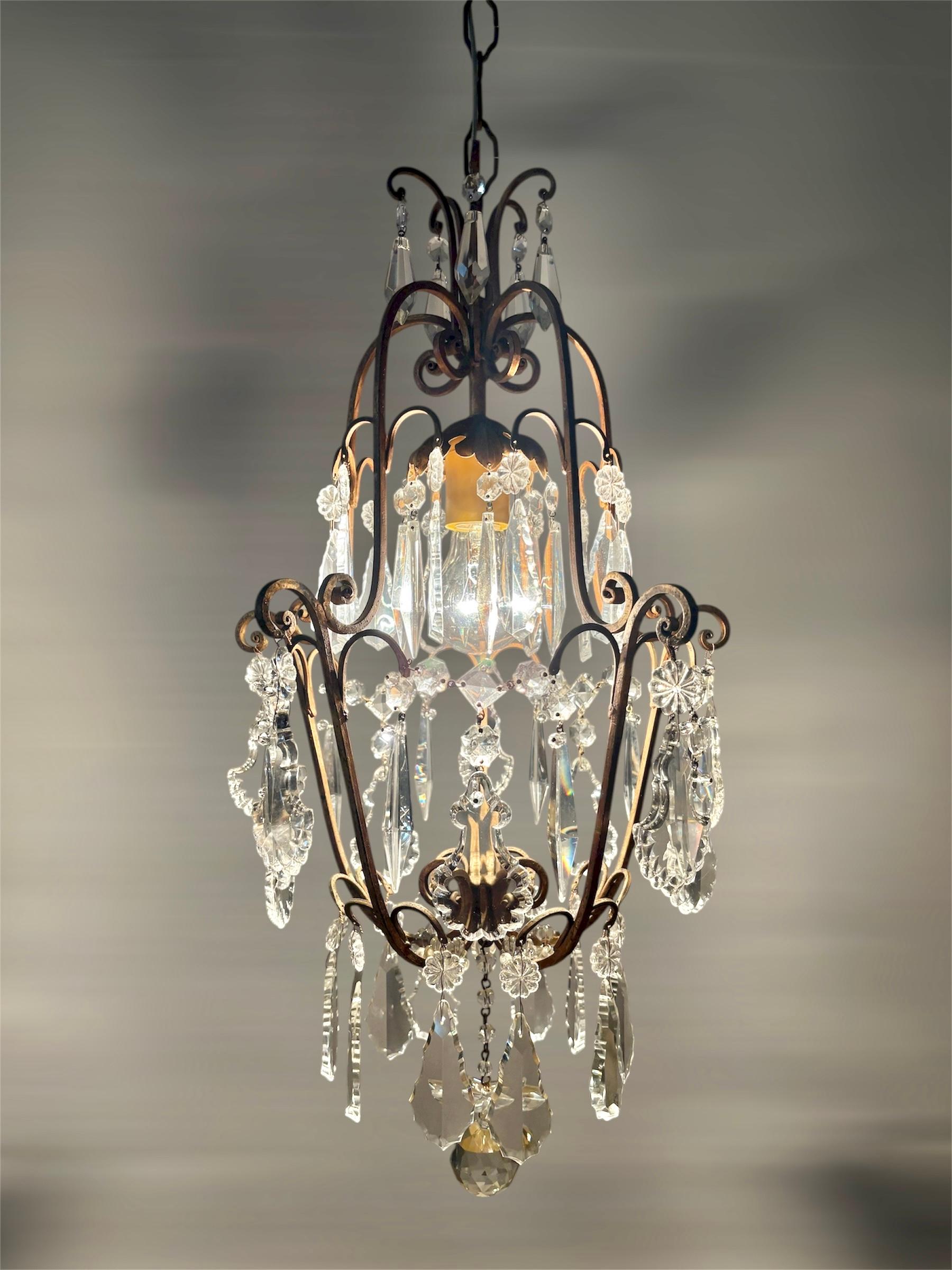 Eleganter italienischer Käfigkronleuchter aus den 1950er Jahren mit verschnörkeltem, vergoldetem Metallrahmen und hochwertigen, facettierten Kristallprismen und -tropfen. Die offene 