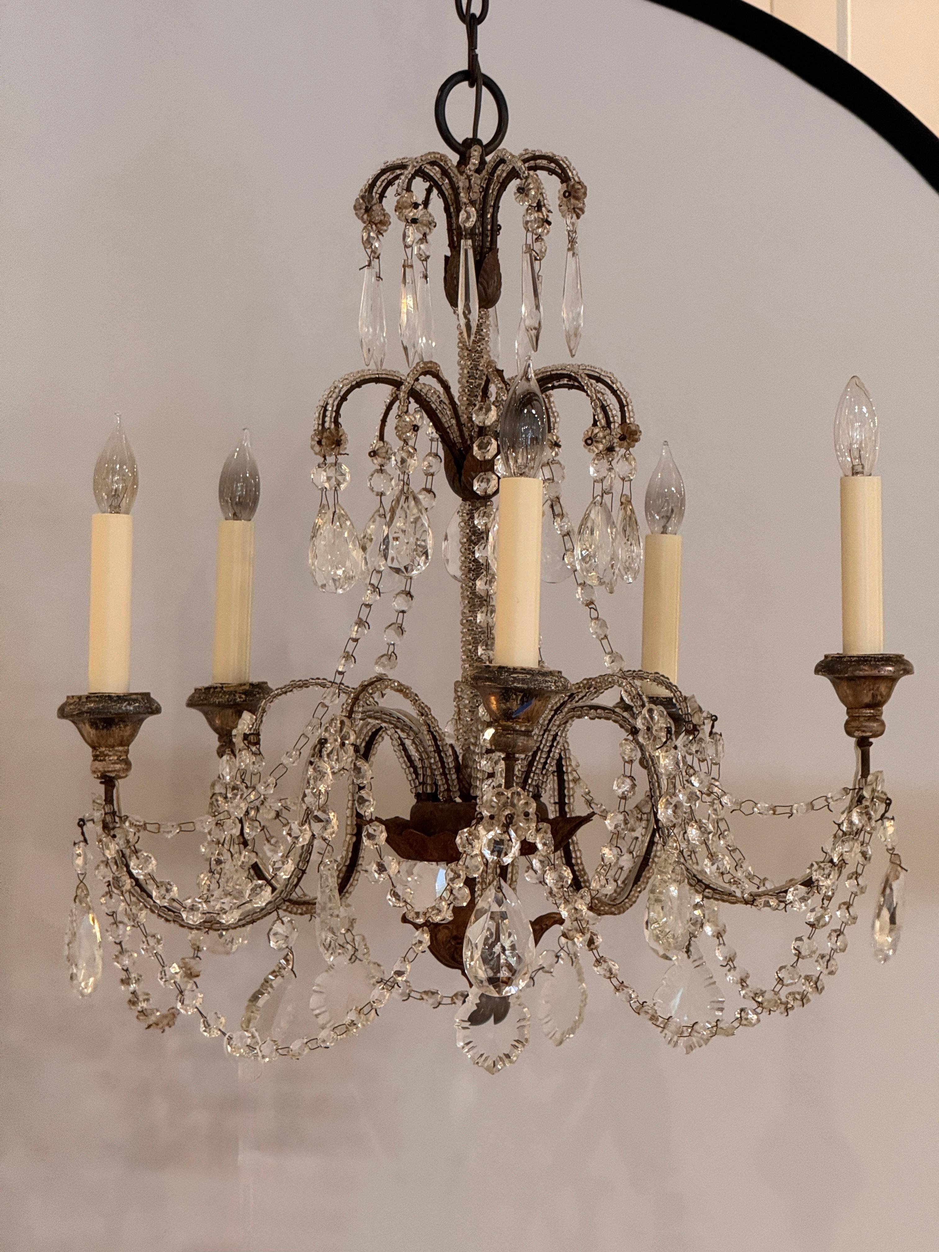 Six-light Italian chandelier with a beaded metal frame and swags of faceted crystal garlands. Decorative teardrop prisms and delicate spear drops add brilliance to the scrolling arms and upright crest. Rich patina on the metal base contrasts with