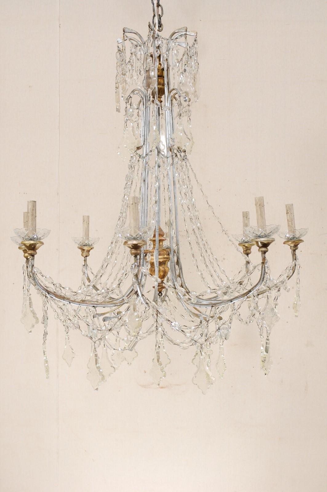 An Italian crystal eight-light chandelier from the mid-20th century. This vintage chandelier from Italy features swooping strands of Italian glass which flow downward from the two-tiered crystal waterfall top. The eight silver metal arms are draped