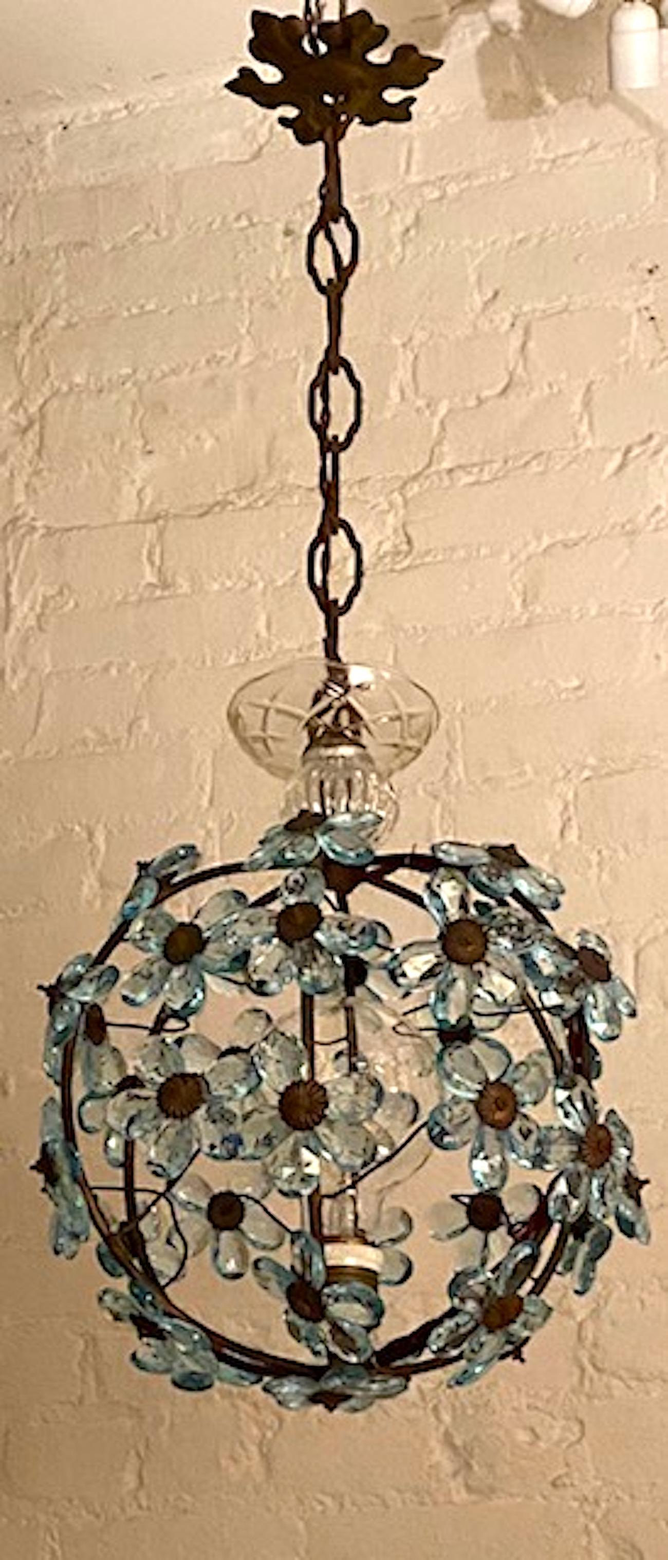 A charming Italian globe shape pendant light of light blue crystal flowers, circa 1960. The iron frame has an antique distressed bronze / brown patina. It is mounted with pale blue faceted crystal petal flowers. Just above the globe is a hand blown
