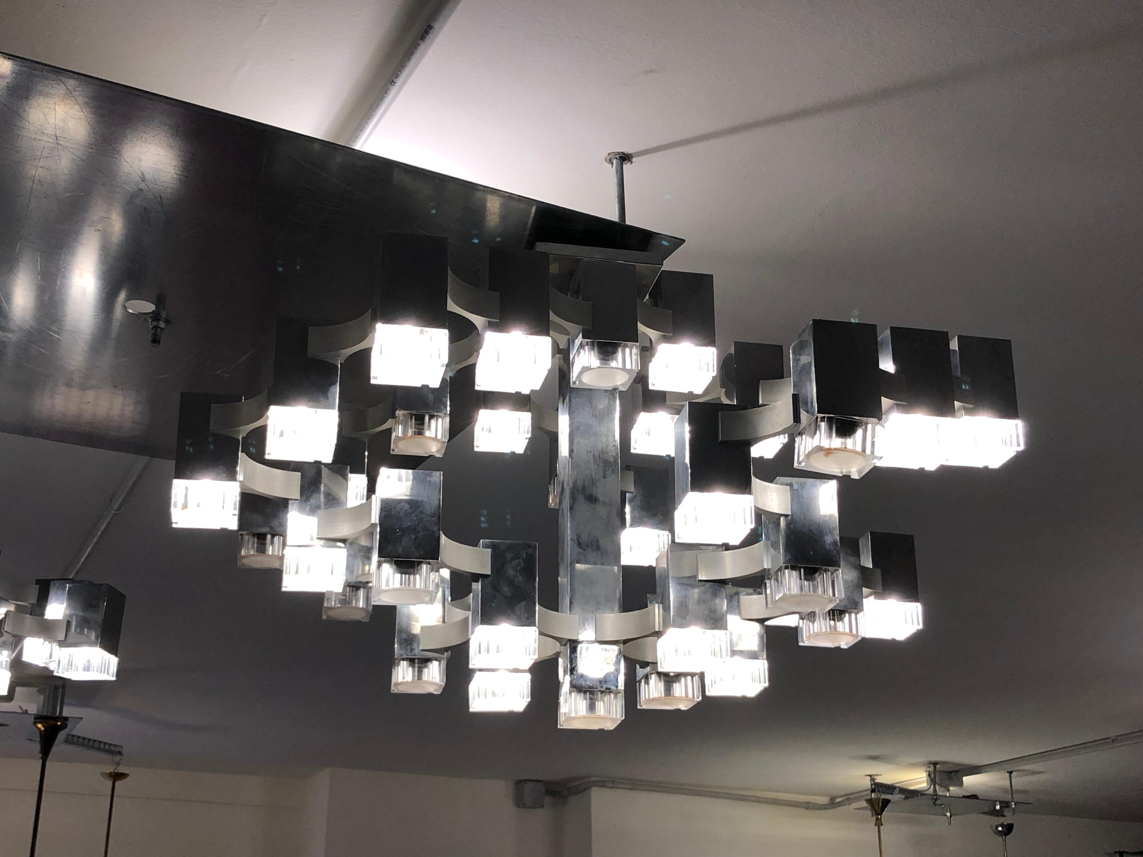 This cubic chandelier was designed by Gaetano Sciolari, and produced in Italy during the 1970s. It features a chrome frame with Perspex shades. Set of two. Each chandelier can be both a ceiling lamp or a pendant lamp (it will be provided the