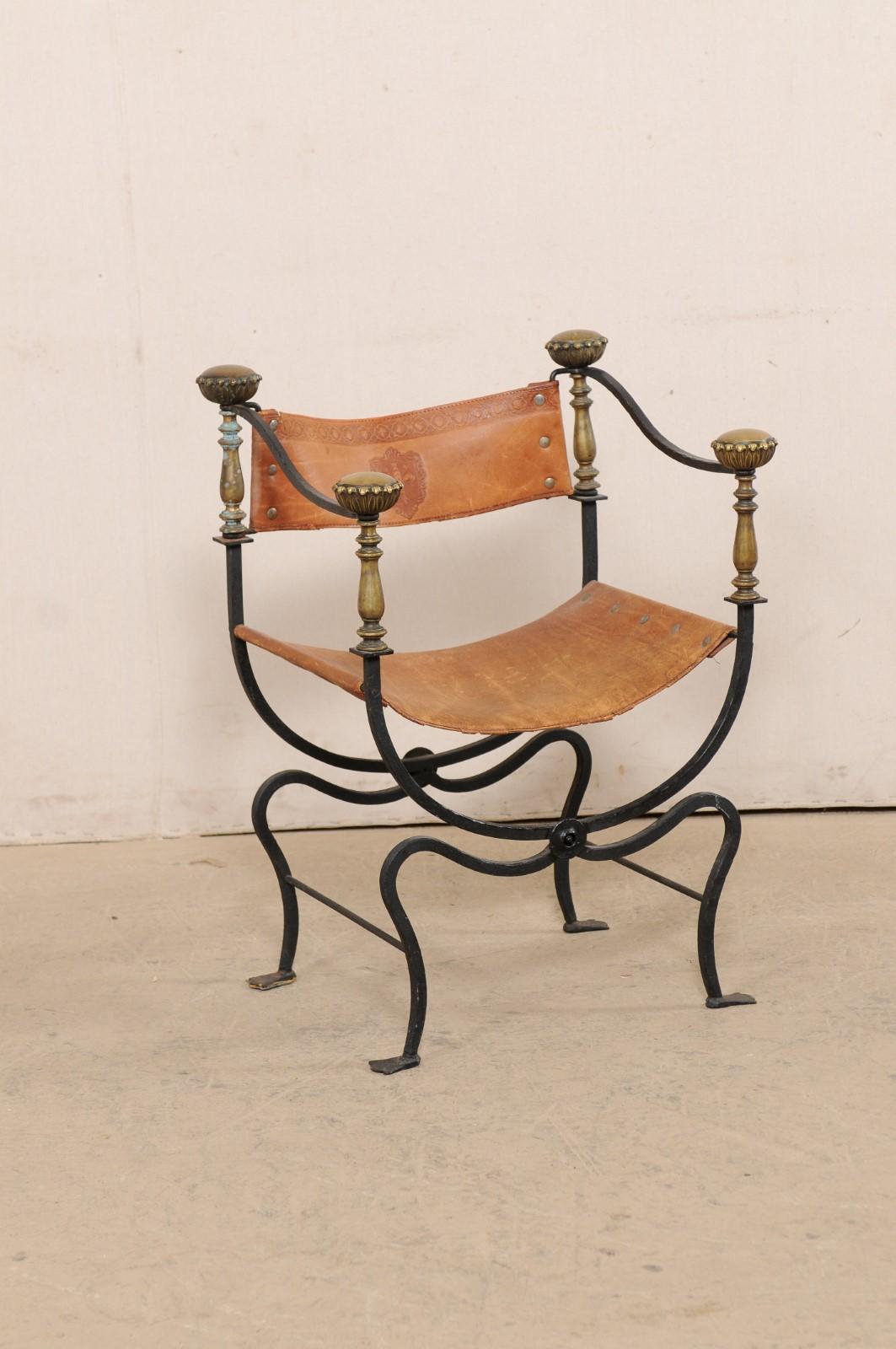An Italian curule Savonarola iron and embossed leather chair from the early 20th century. This antique curule chair from Italy, also commonly called a Savonarola, is defined by the signature frame which upper support curves down half way to meet and