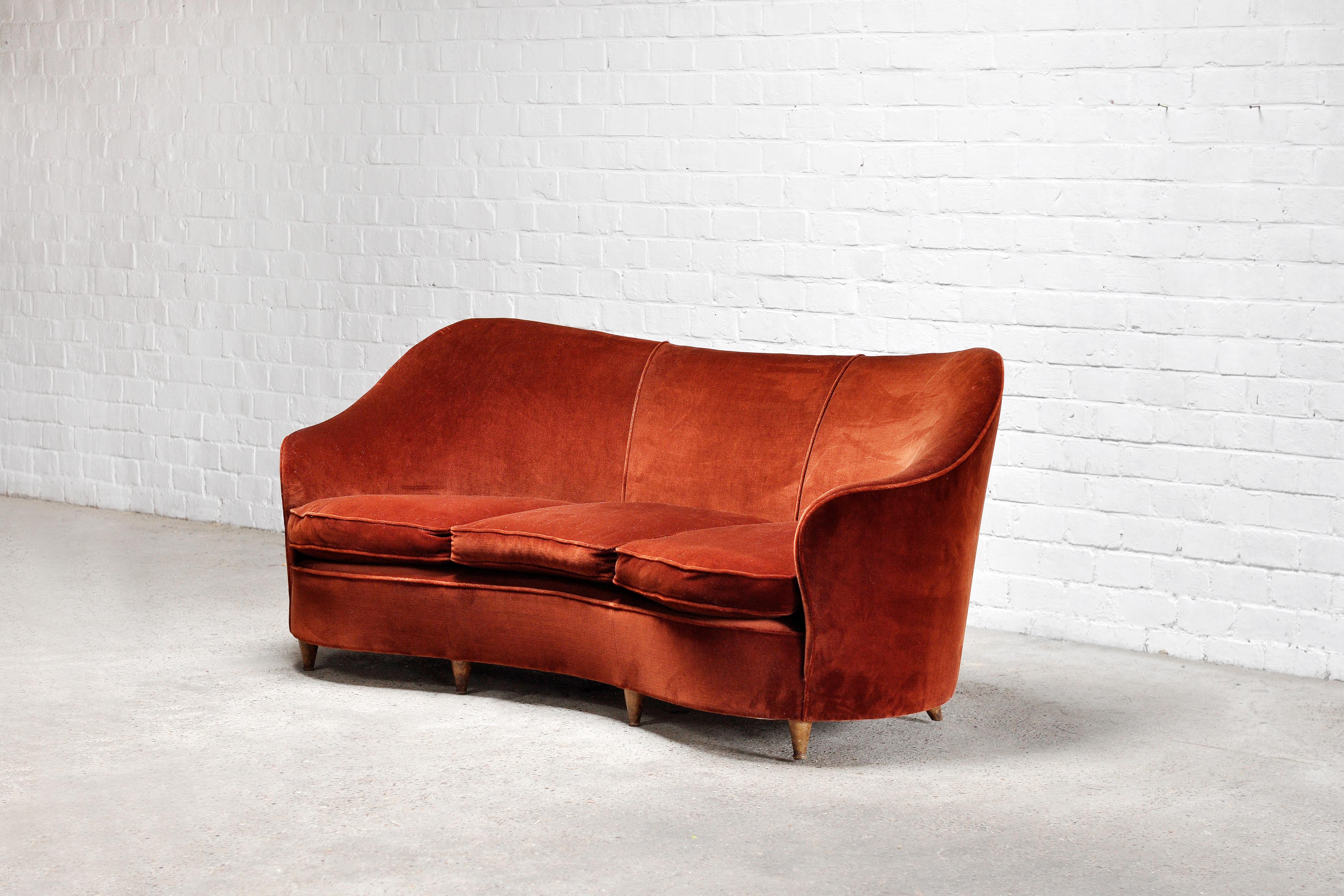 A beautiful curved 3-seater sofa designed by the architect and designer Melchiorre Bega in Milan, Italy 1950’s. The sofa features its original warm red/brown velvet upholstery and has conical feet made out of wood. Its organic shapes and lines