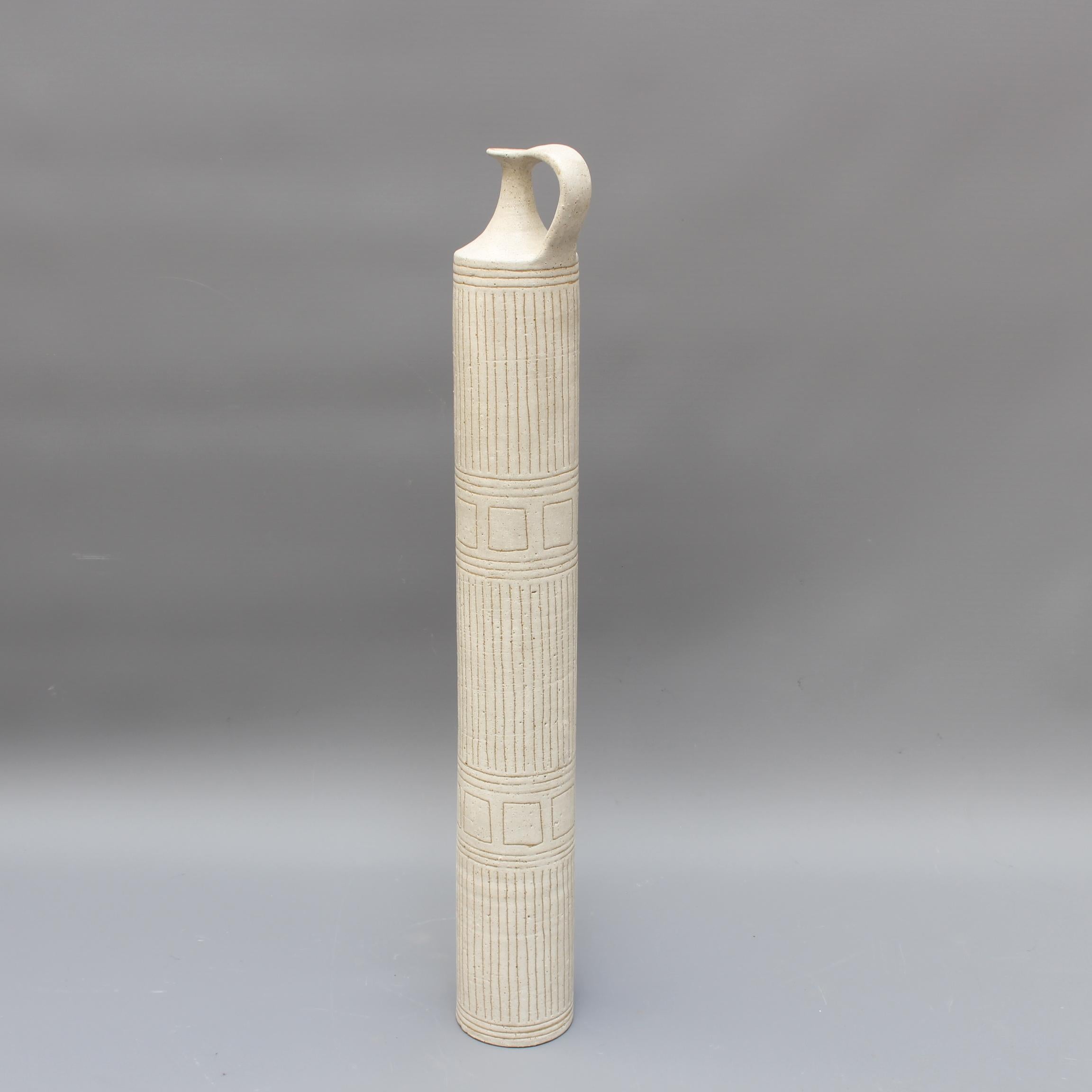 Stunningly tall cylindrical ceramic vase with single, amphora-style handle and Eastern motif on an elegant beige earthenware surface, by Bruno Gambone (circa 1970s). This substantial yet gracefully elongated decorative vase is a work of art whose