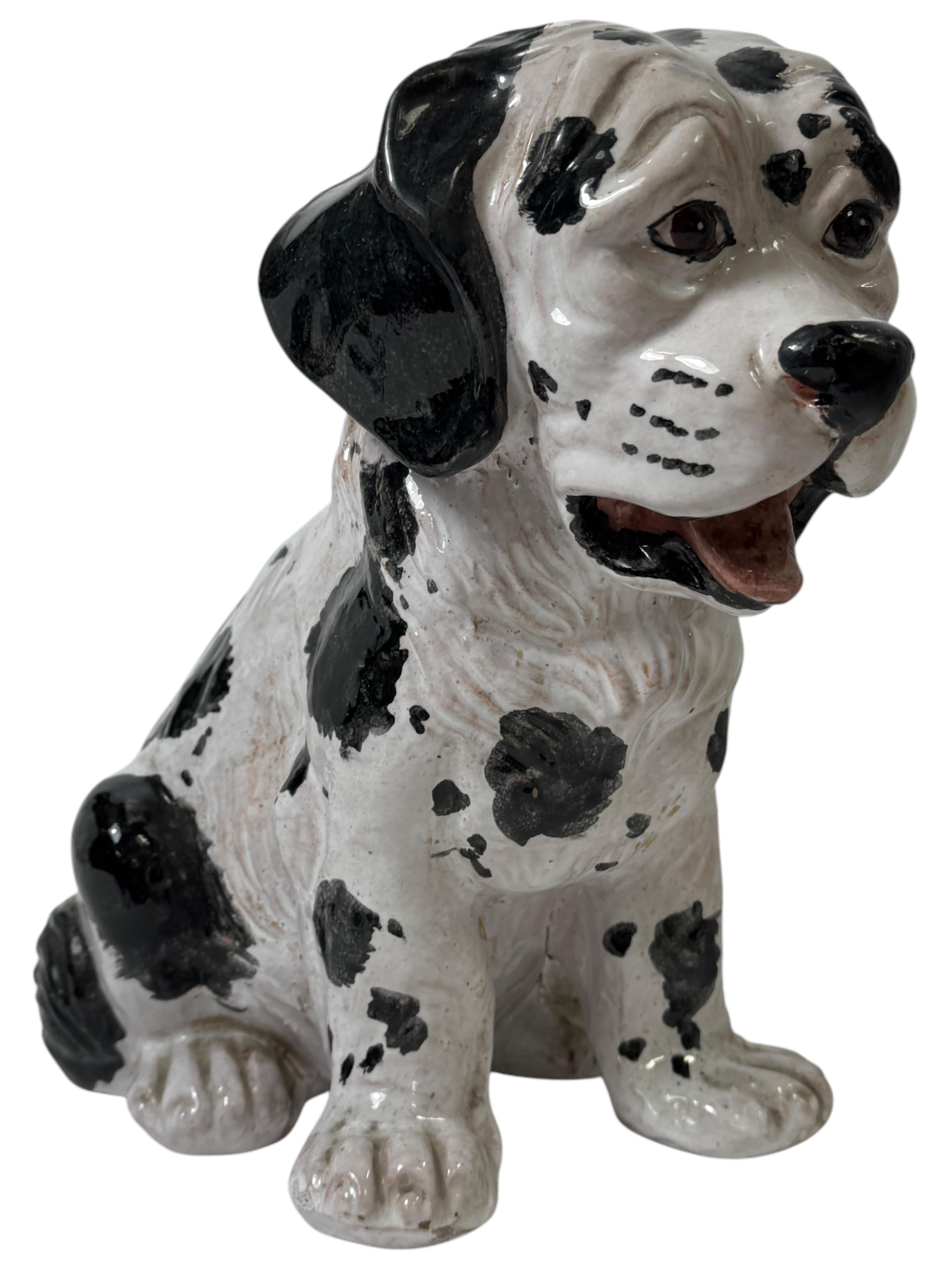 Una scultura vintage in terracotta italiana del Mid Century Modern. Un'opera figurata di animali prodotta intorno agli anni '60 che raffigura un cane dalmata modellato seduto. Terracotta smaltata bianca e nera con bellissimi riflessi. Dipinto con