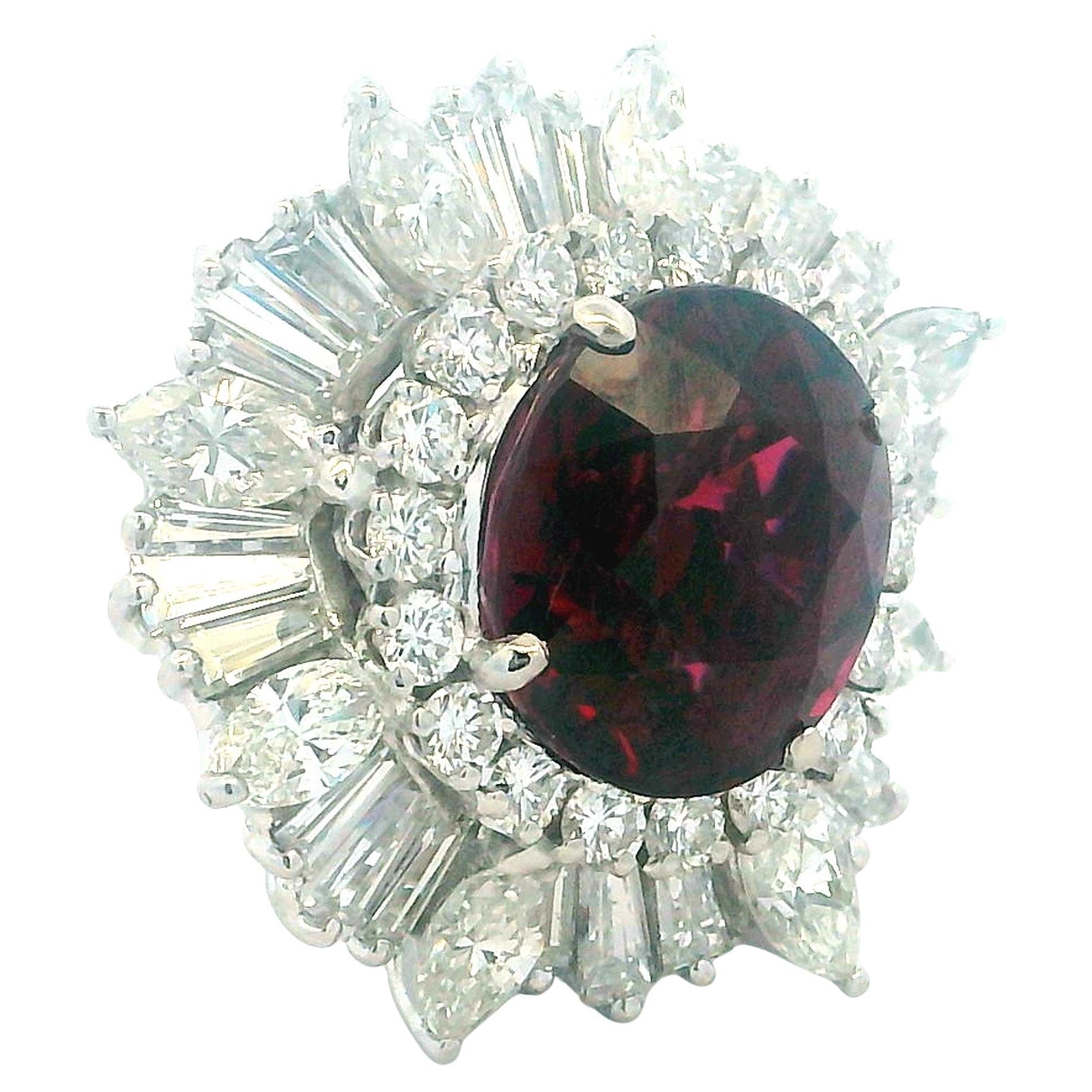 Elegante anillo de cóctel italiano de Damiani, finamente elaborado en platino y engastado con un granate ovalado de rico colorido que pesa aproximadamente 6,15 quilates. El tono rojo intenso de la gema está realzado por una espectacular envoltura de