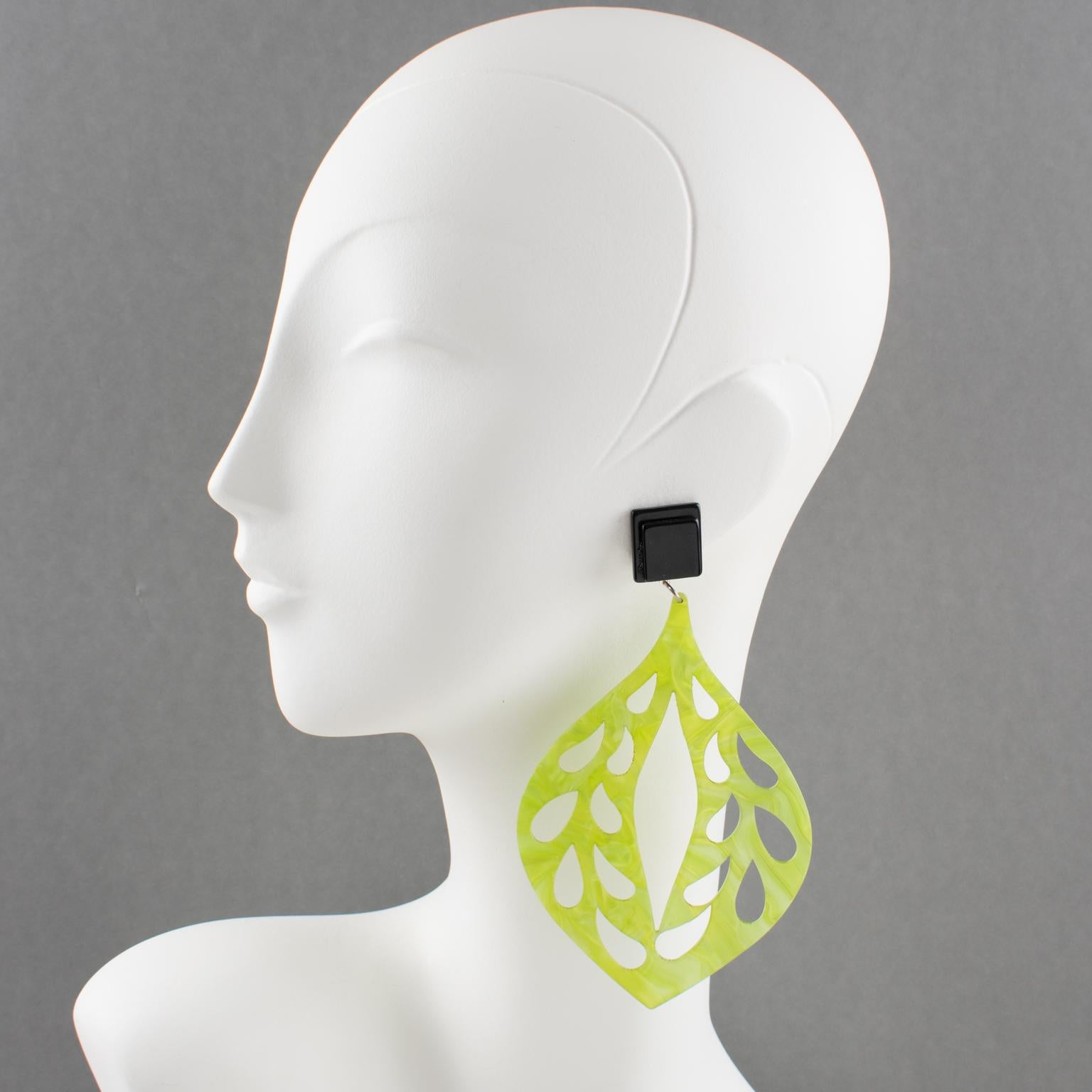 Spectacular Italian designer studio Lucite or resin dangling shoulder-duster clip-on earrings. Oversized drop shape all carved and see-thru in lime green color with a moon-glow textured pattern. Clip fittings in black color with a laminated pattern.