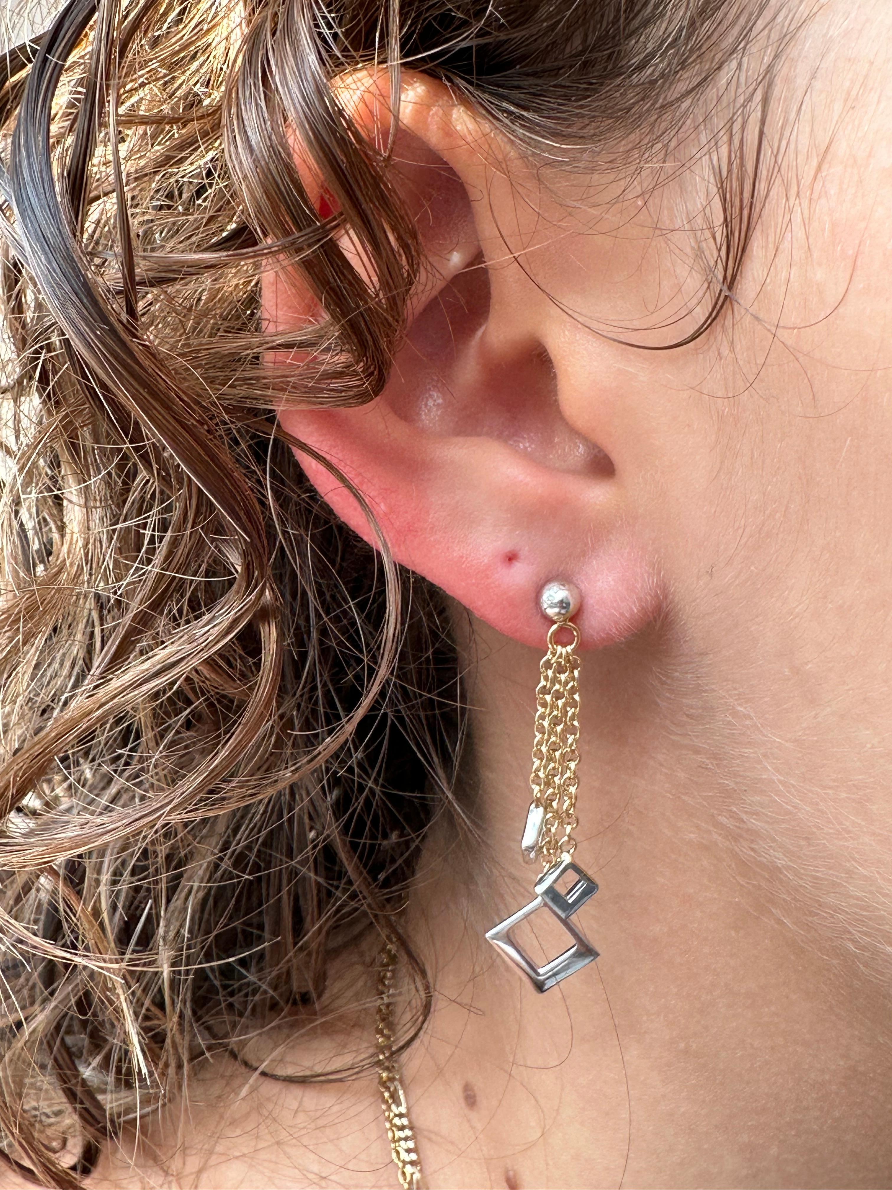 These Italian Dangle Earrings are a refined example of contemporary elegance, crafted in luxurious 18kt yellow and white gold. Designed to captivate, they feature a dynamic composition of three delicate rows, each culminating in a striking squared