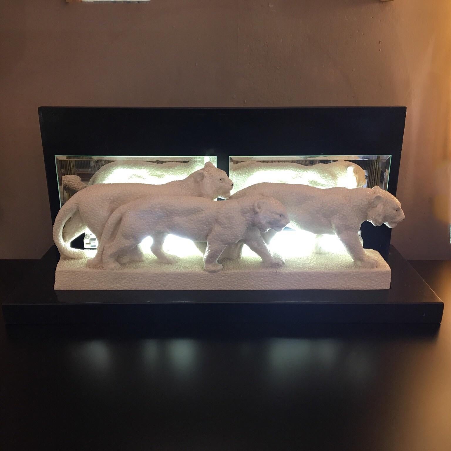 Italian decò lamp sculpture with resin lionesses, black lacquered wood base with two original belleved mirrors on the bottom line, electrical system consisting of two neon lights, the black lacquered wood includes the resin lionesses sculpture. They