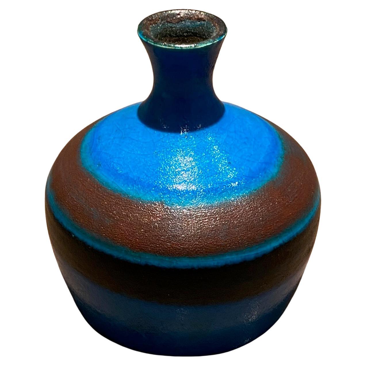 Glänzende blau-braun emaillierte kleine Vase von Bruno Gambone
Maße: H 15 cm x L 14 cm
Am Sockel vom Künstler signiert Gambone Italy.


