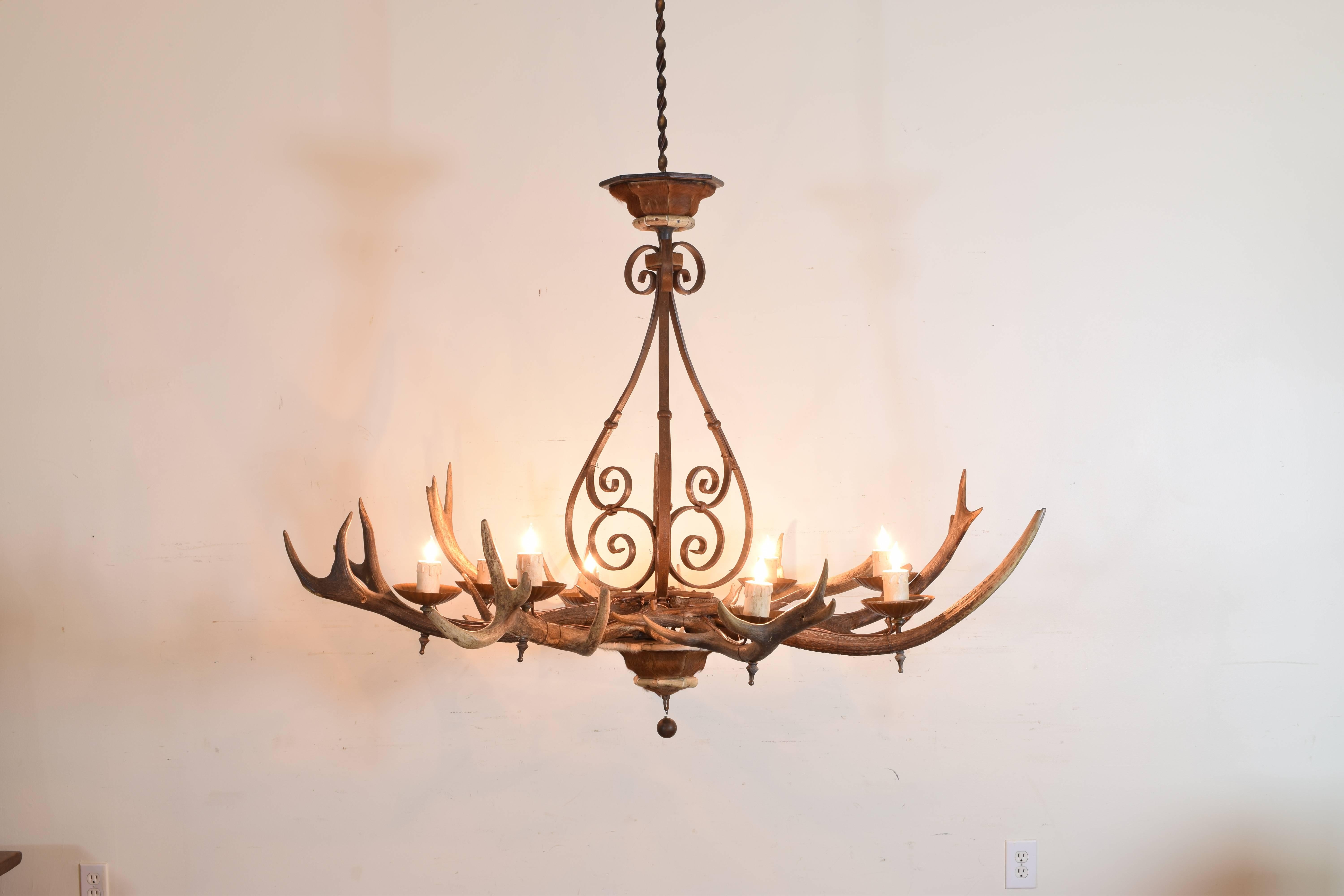 Uniquely constructed chandelier constructed of antlers, wrought iron bracing, hide and wrought iron central stem, hide canopy and terminal, UL wired.