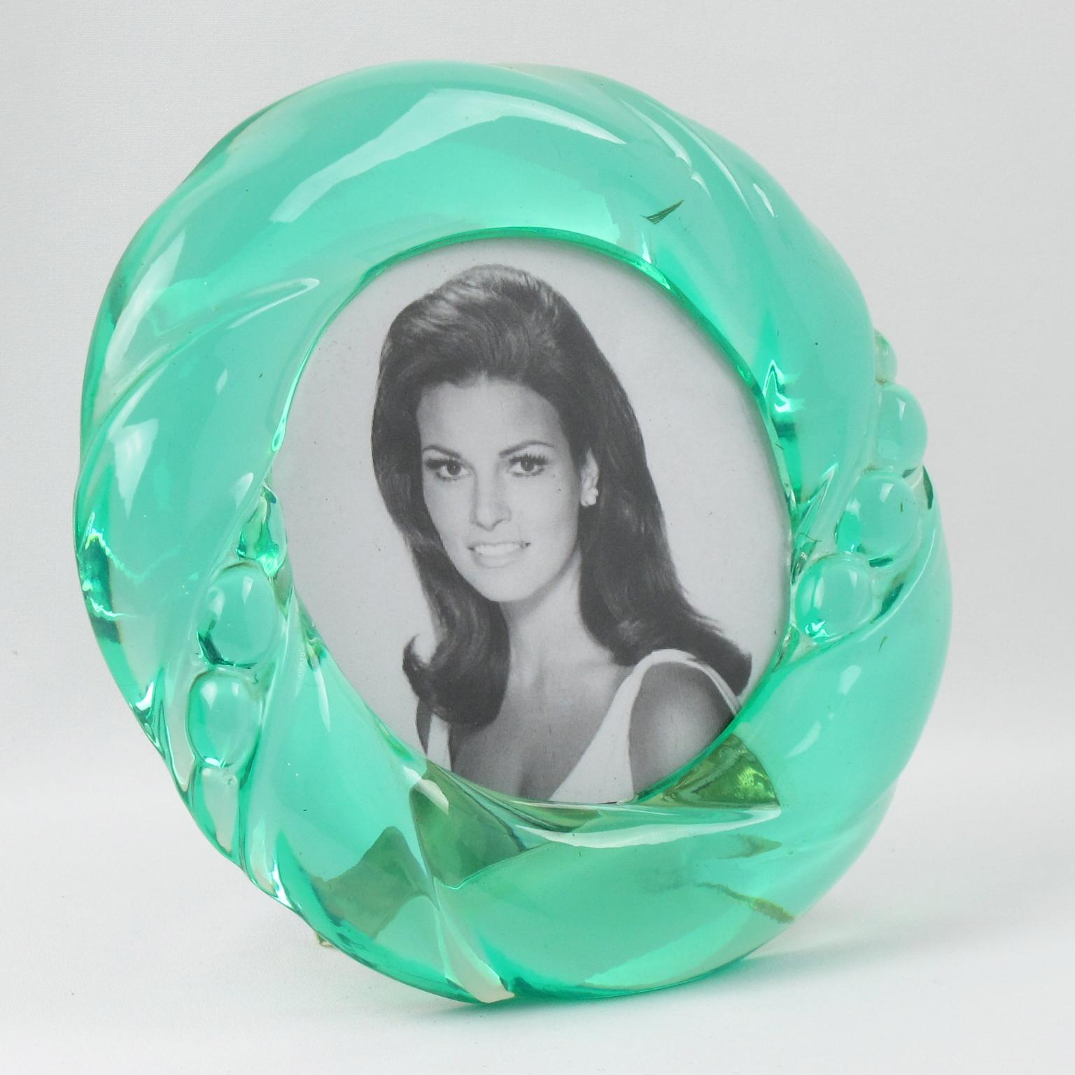 Stunning modernist picture photo frame made in Italy in the 1970s. Featuring extra-thick Lucite round frame with carving in gorgeous transparent aqua green color. Fixed Lucite easel at the back. No visible maker's mark.
Measurements:
Overall: 7.50