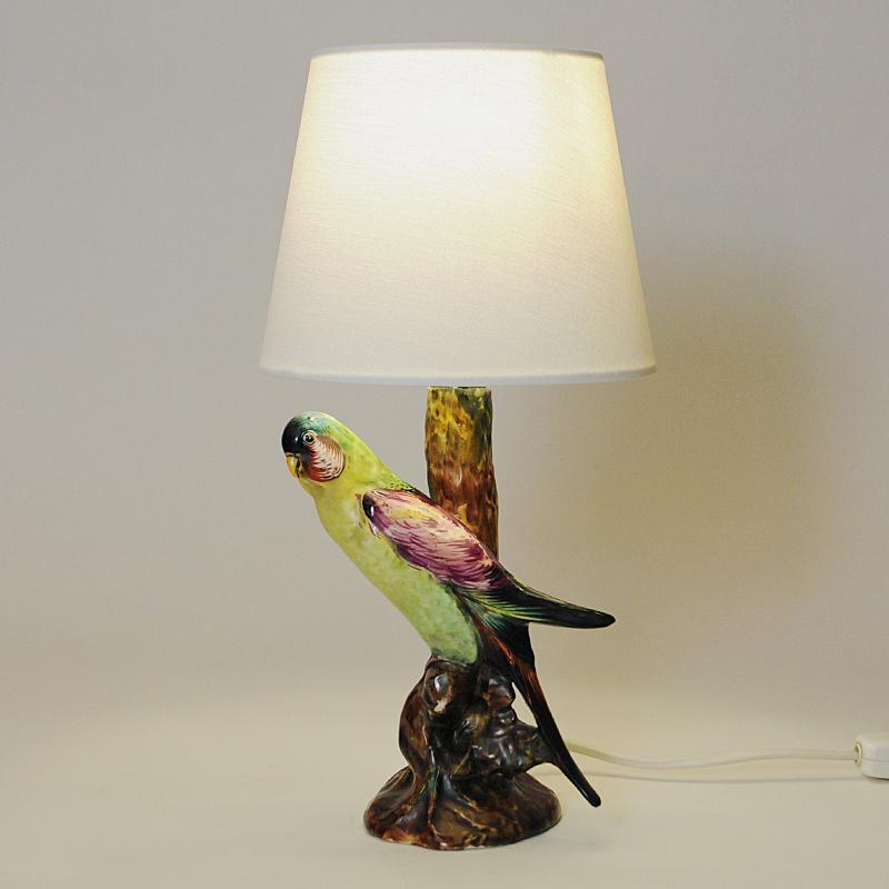 Lovely Italian glazed ceramic table lamp from the 1950s with a colorful bird on the pole front. The lamps pole are designed as a tree trunk with the bird- in which is a budgerigar - sitting on a branch i front of the lamp. This realistic bird has