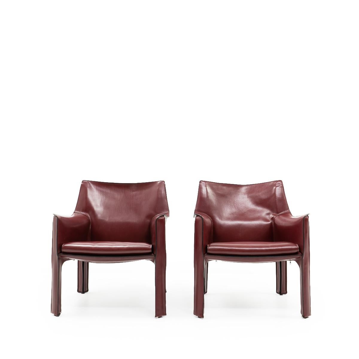 Set of two Cab 414 armchairs in a deep, bordeaux red leather by Mario Bellini for Cassina.

These very comfortable lounge chairs are built up with a tubular steel frame over which foam and thick saddle leather is fitted. The leather skin is kept