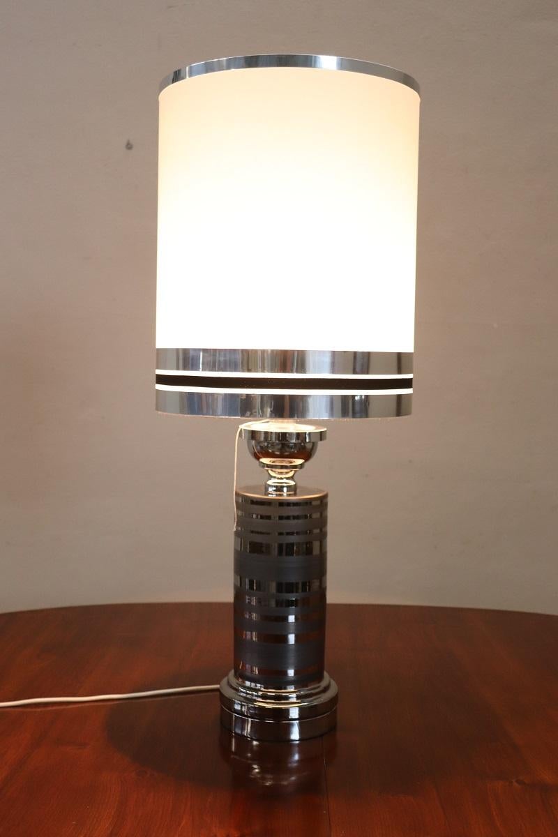 We present this beautiful table lamp made in Italy in the 1970s. The lamp is made of ceramic decorated with silver-colored enamel. The ceramic part is harmoniously combined with a base and a high terminal part in chromed metal.
A high lampshade