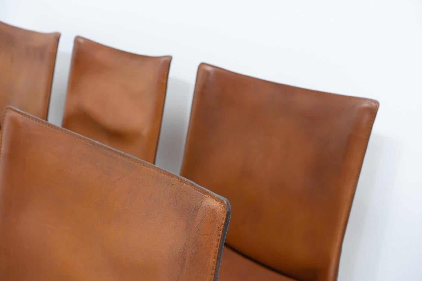 Set di sei sedie Cab 412 in pelle marrone patinata di Mario Bellini per Cassina.

La sedia Cab è costituita da un telaio tubolare su cui viene applicata una spessa pelle di sella; la pelle viene mantenuta in posizione con cerniere sulle gambe