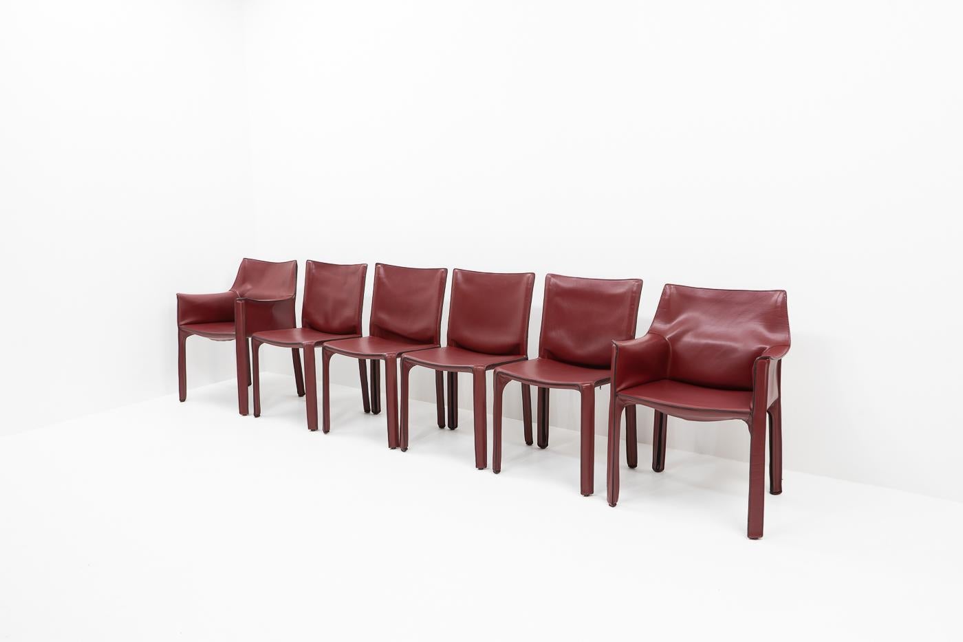 Set of two Cab 413 armchairs and four Cab 412 side chairs in red leather by Mario Bellini for Cassina.


These very comfortable lounge chairs are built up with a tubular steel frame over which foam and thick saddle leather is fitted. The leather
