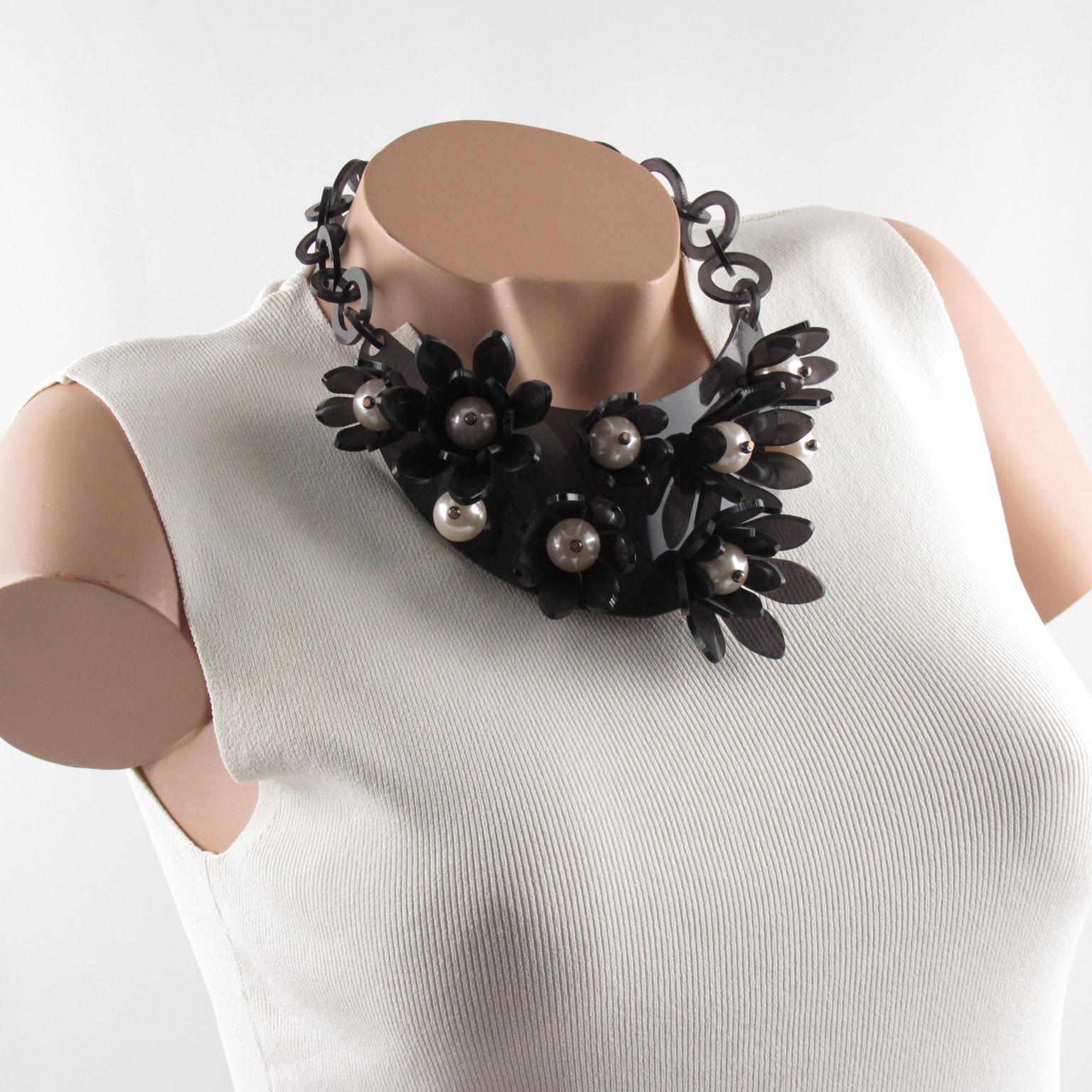 This impressive transparent dark gray Lucite or Plexiglass bib choker necklace was crafted by Italian designer Manoa2 (Milano 1980 - 1985). The collar shape has a large curved bib topped with dimensional flowers and huge pearl-like beads. The