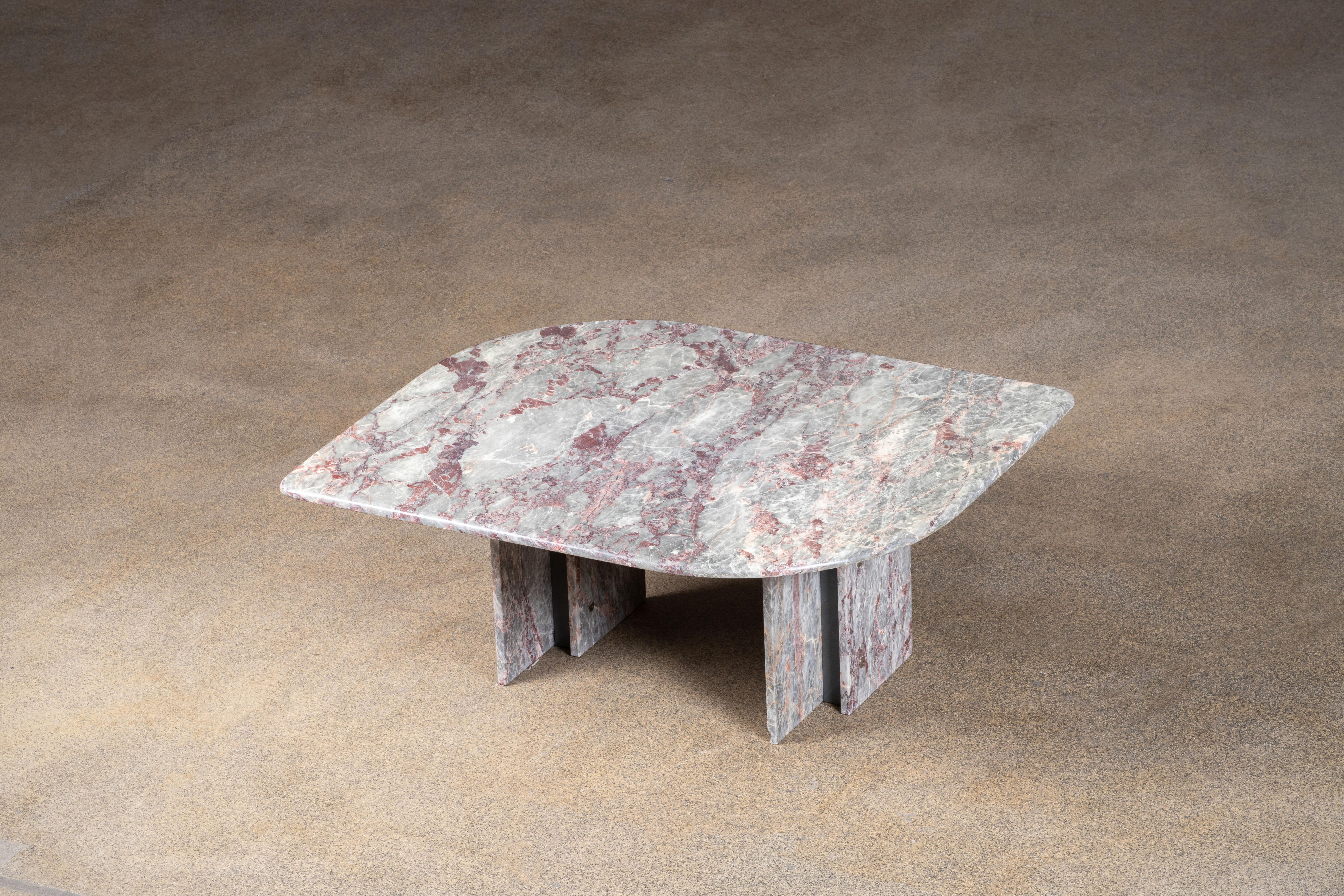 Schöner Tisch aus grauem, weißem und rosa Marmor.

Die schwere, augenförmige Platte ruht auf zwei Marmorblöcken mit einer Metallstruktur dazwischen.

Dieser Tisch sticht wirklich hervor.

