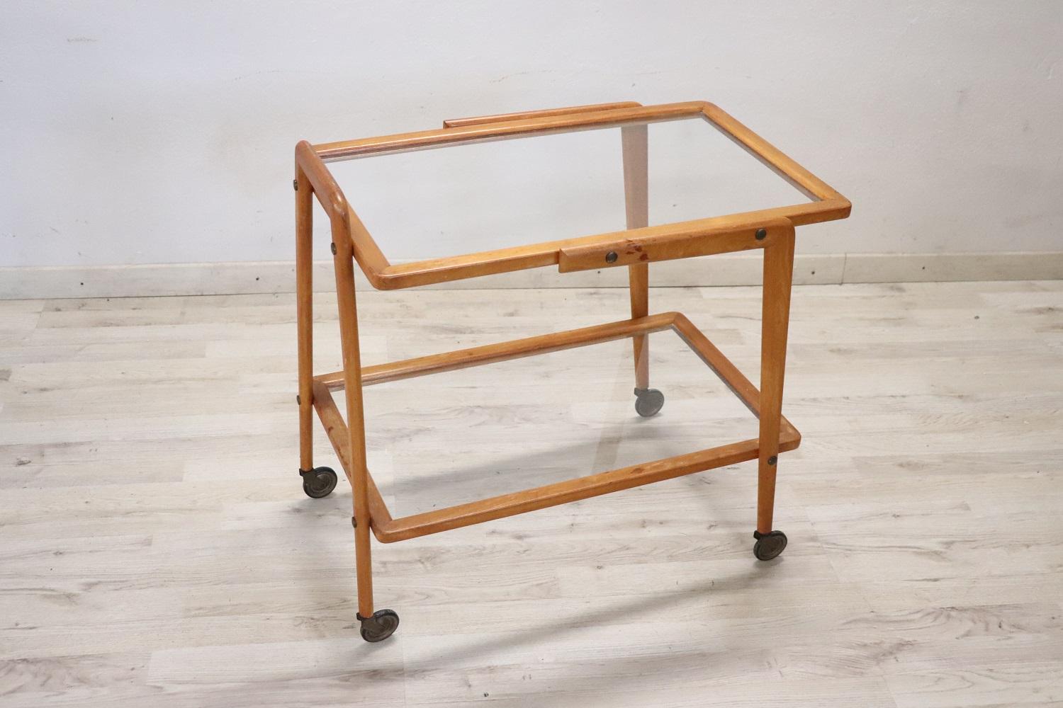 Rare 1950s Italian desgin serving bar cart. Made of beech wood equipped with two glass shelves and brass wheels for convenient movement. Perfect for serving drinks to your guests. Vintage good conditions.