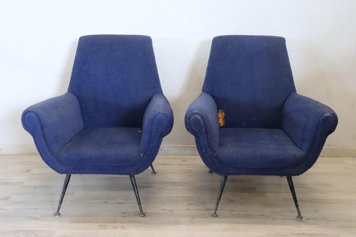 Lovely italian design pair of armchairs in original used conditions 1950s. In original iron legs and brass feet with sponge padding and blue bouclé wool covering. This pair of armchairs was created by Gigi Radice for Minotti. The low price compared