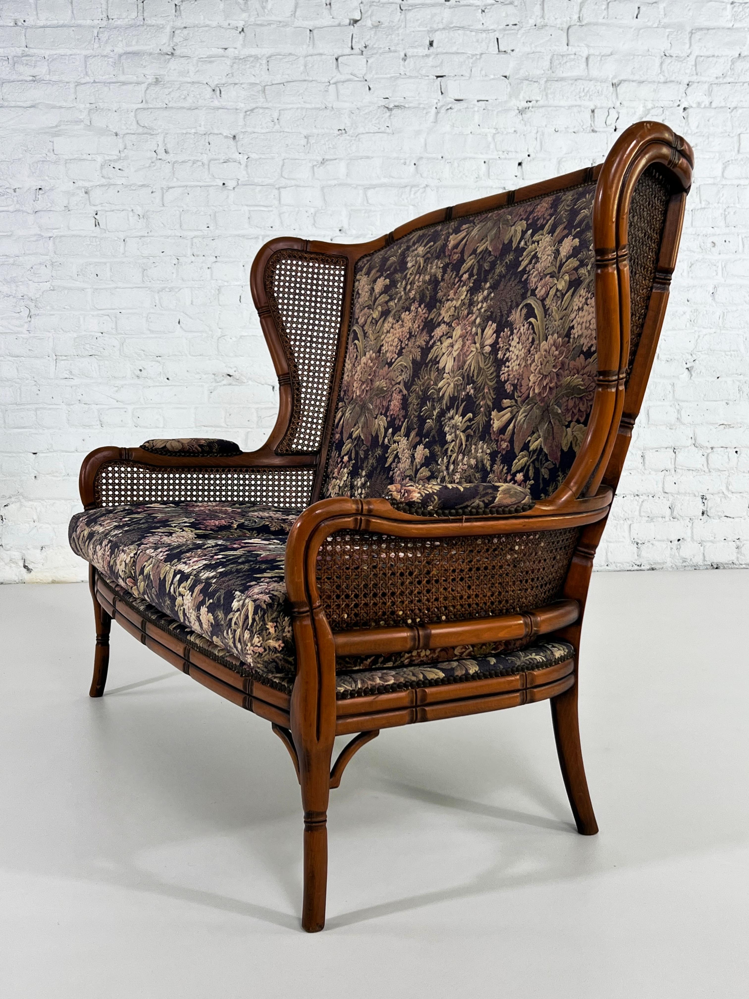 Italian design two seater sofa with sculpted wooden structure bamboo effect, wicker cane wingback finishes adorned with a romantic deep blue and colored floral fabric
 