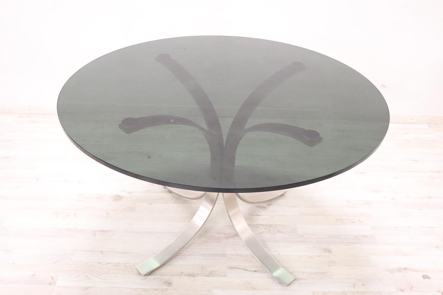 Beautiful italian design round dining room table, 1970s. The table has wavy steel legs and a thick smoked glass top. The top can be separated from the legs for easy movement. Good general condition, small signs of wear on the top. Perfect table for