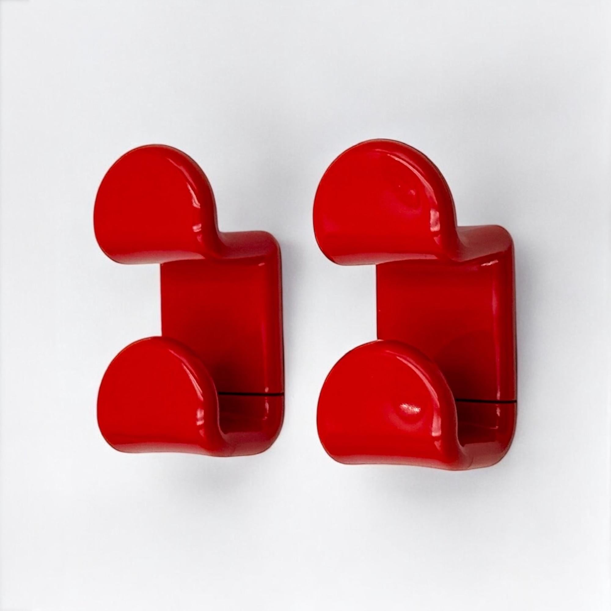 Straordinario set di appendiabiti anni '70 disegnato da Ambrogio Rossari per Gedy. Realizzati in Italia, questi ganci presentano un'audace struttura in plastica rossa con una silhouette elegante e sinuosa che riflette perfettamente lo spirito