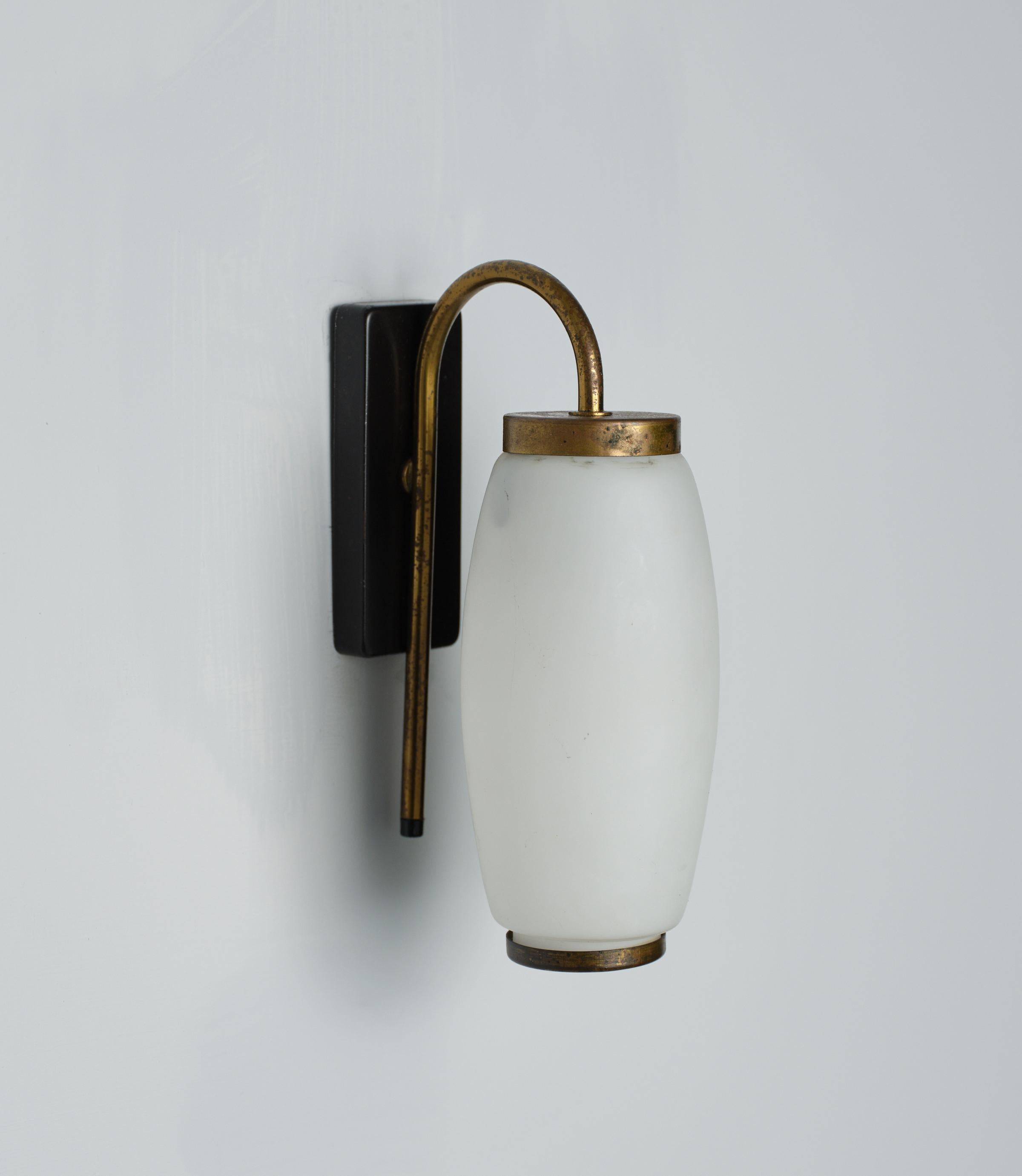 Presenting one vintage Italian wall lamp. Crafted in the 1950s, these elegant appliques feature a combination of brass, black lacquered metal, and opaline glass, showcasing authentic design from the era. The brass boasts its original patina, while