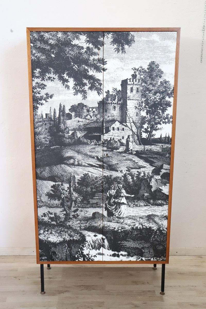 This two-door wardrobe of Italian design from the 1970s is truly special. Made of plywood characterized by a large printed decoration on the doors. A classic scene from the ancient era with characters and a castle in the background. Interior
