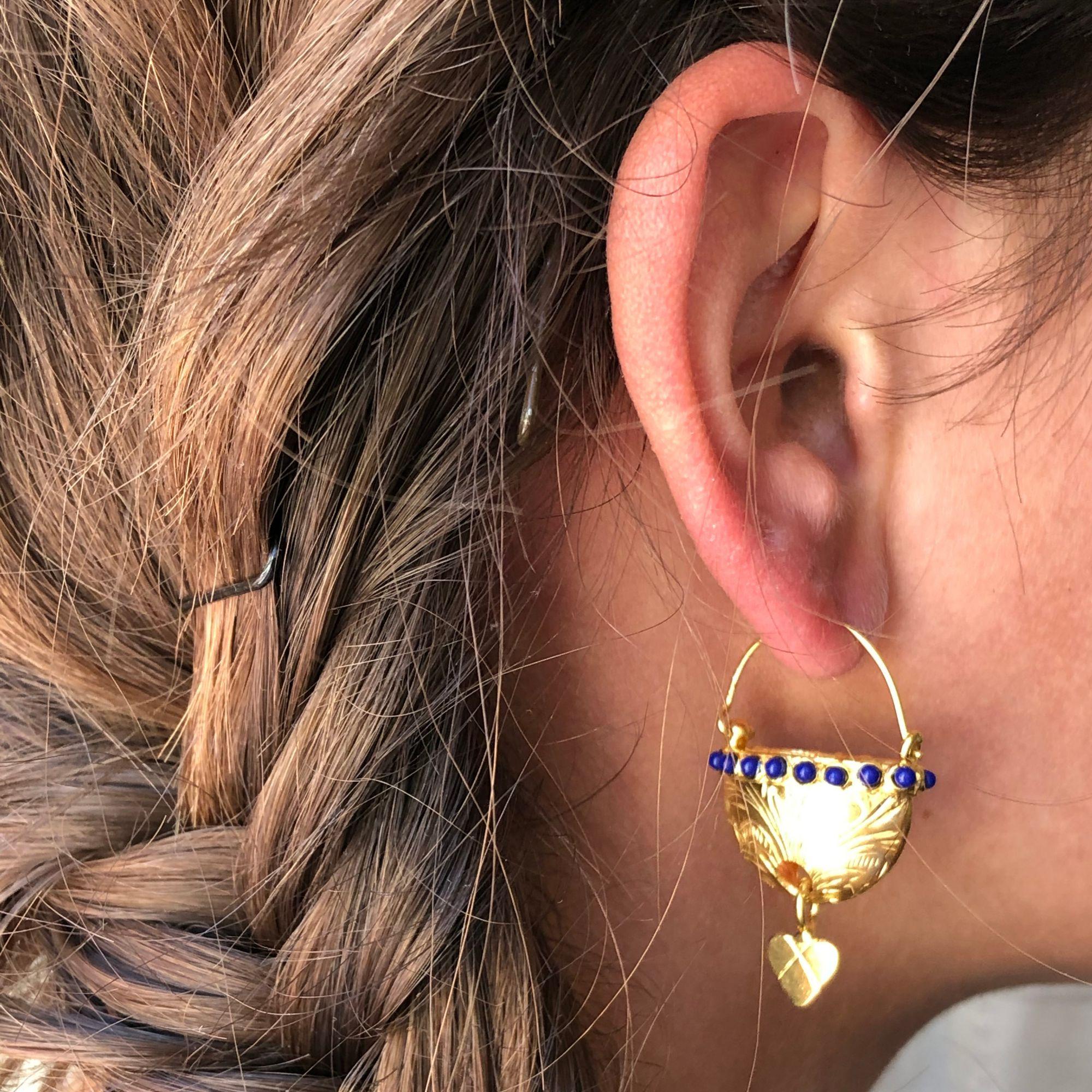 For pierced ears.
Earrings in yellow vermeil, silver and yellow gold.
Pretty lever- back earrings, they are made of a basket chiseled with floral motifs bordered by a line of blue crystal pearls. A small heart hangs from it. The attachment system is