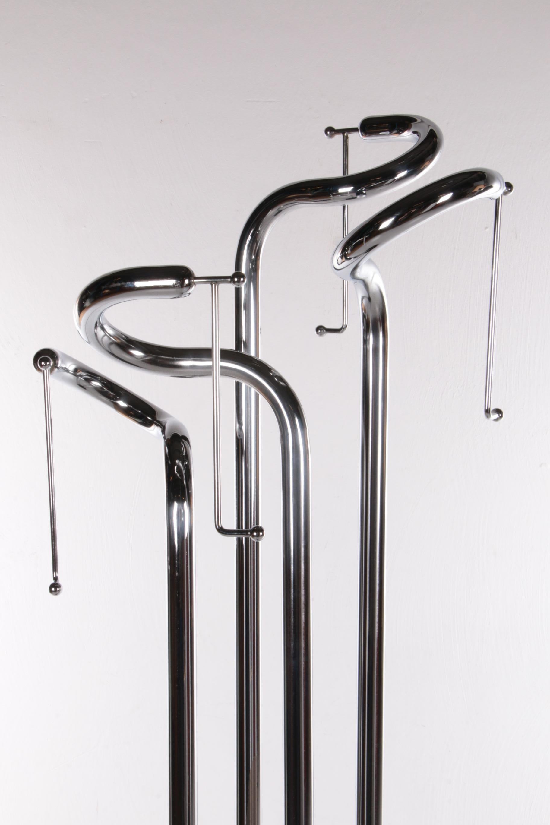 This is a very special model coat rack mounted on a round lacquered wooden base.

Four beautiful heavy chrome tubes are attached to it, each with a thin spout that ends in a ball. The silver metal gives the coat rack a modern and elegant