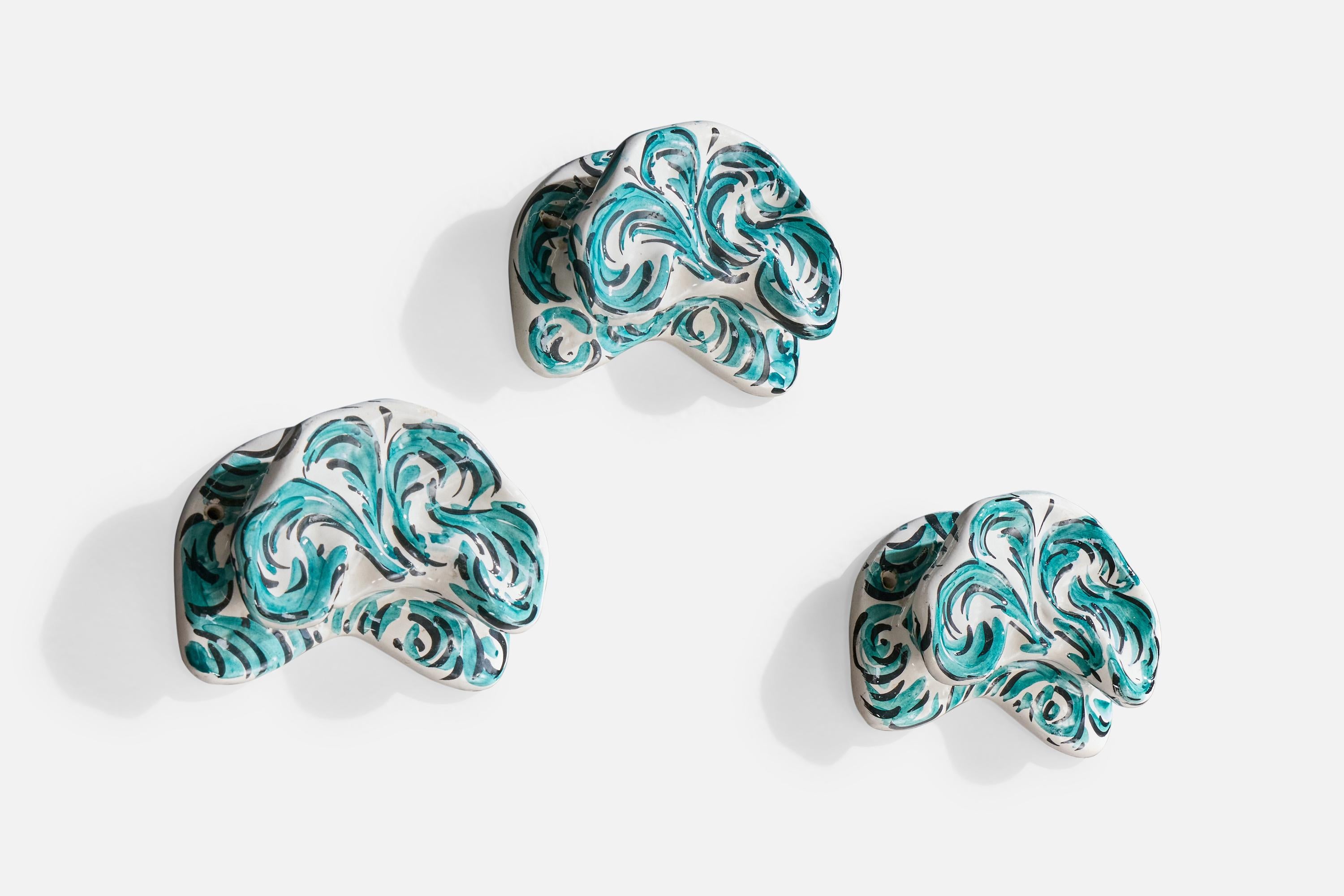 Un ensemble de trois porte-manteaux en céramique peinte en blanc et bleu, conçu et produit en Italie, vers les années 1950.

Dimensions globales (pouces) : 4.5 