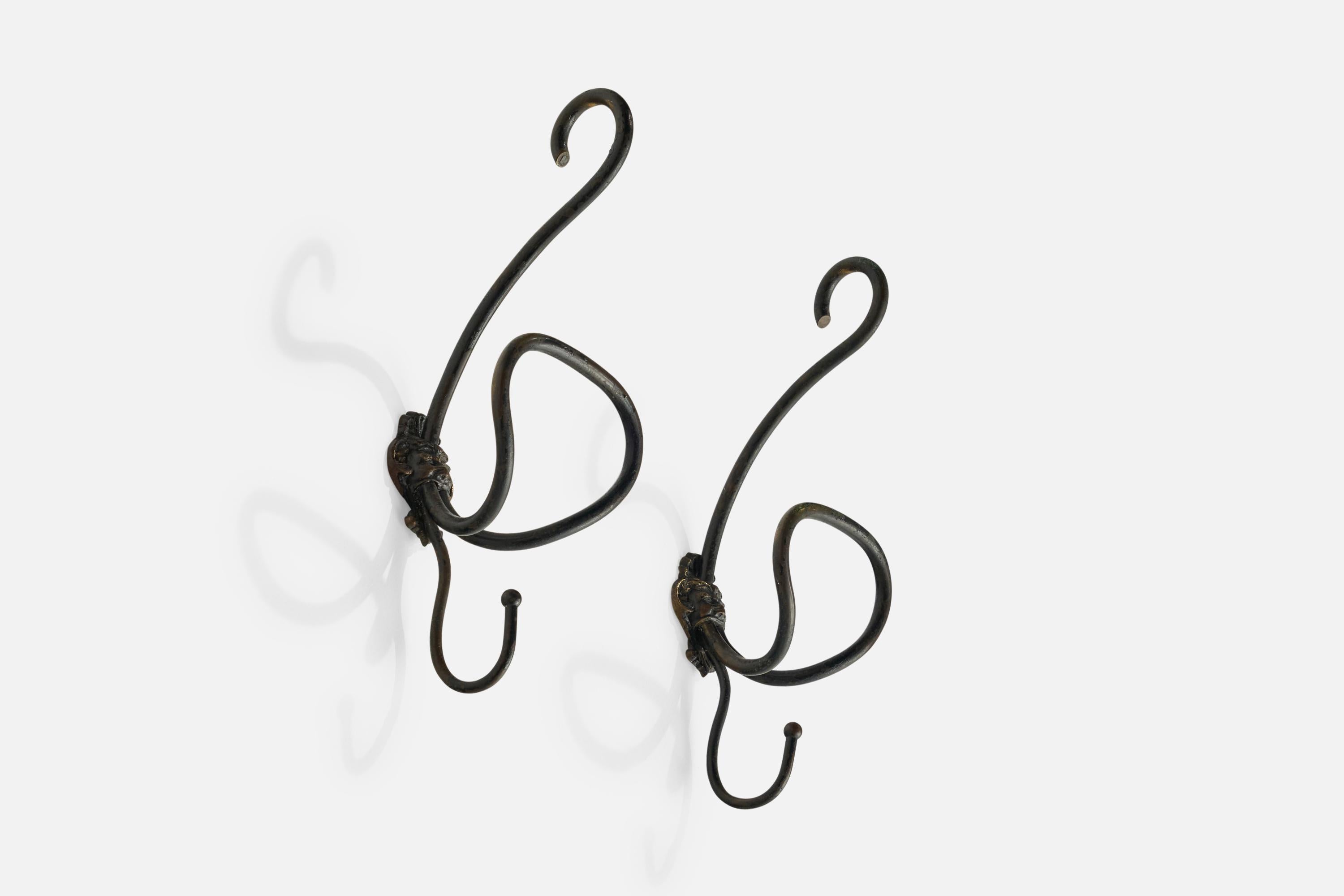 A pair of black-painted iron coat hangers designed and produced in Milan, Italy, 1930s.