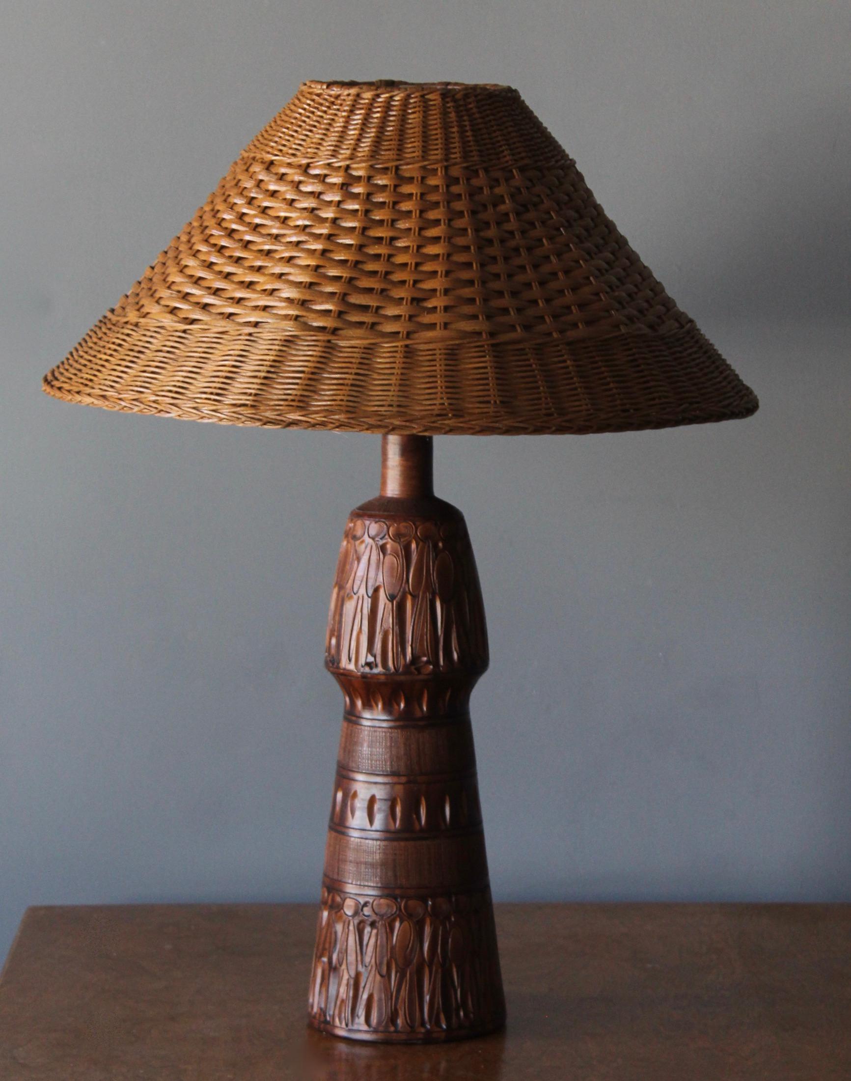 A sizable sculptural table lamp, designed and produced in Italy, 1970s. In glazed and incised ceramic. Assorted rattan lampshade.

Stated dimensions include lampshade.

Other designers of the period include Gabriella Crespi, Donald Judd, Max