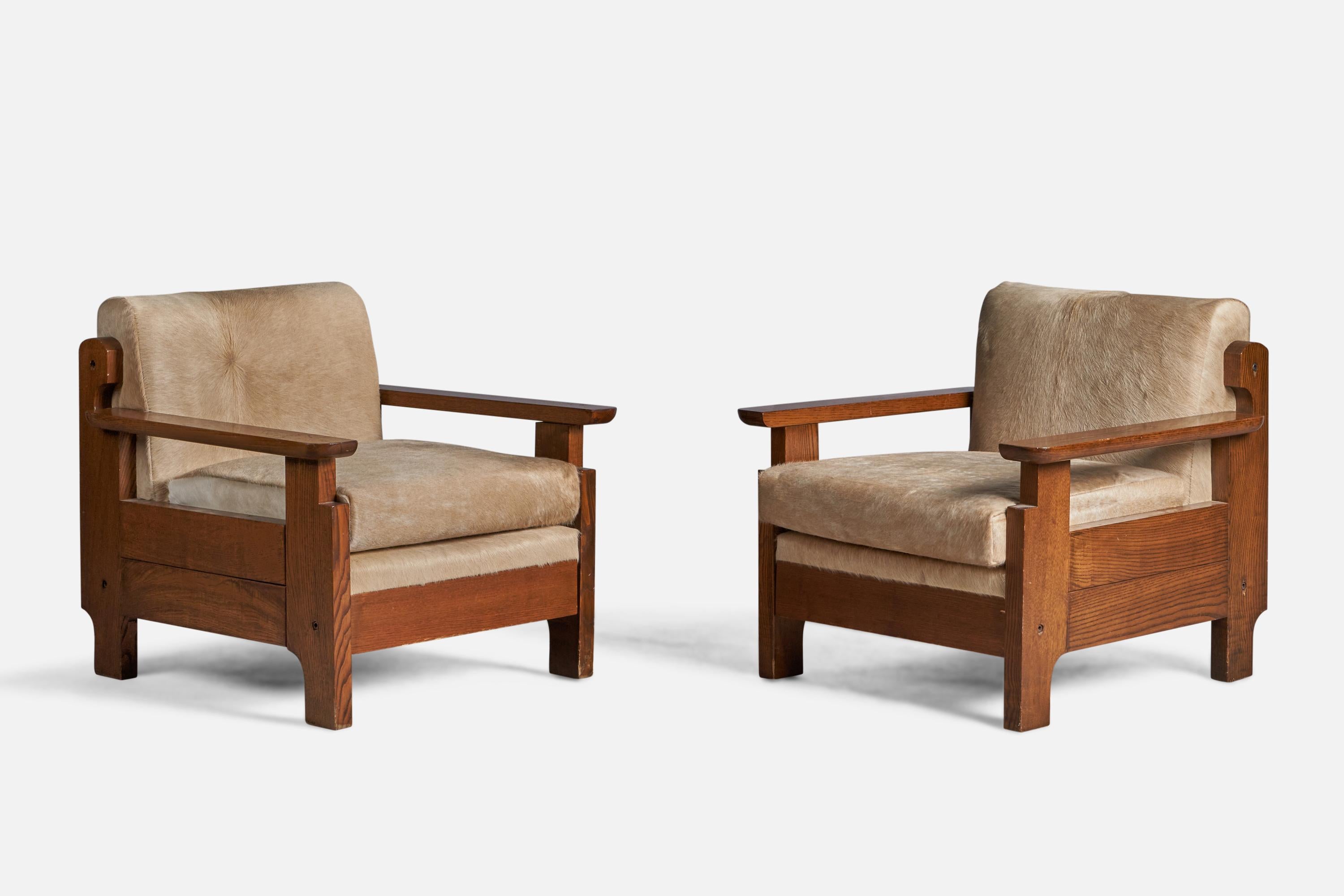 A pair of stained pine and beige cowhide lounge chairs designed and produced in Italy, c. 1960s.

16.5