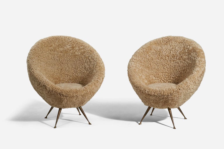 A pair of shearling and brass lounge chairs designed and produced in Italy, 1950s. 

