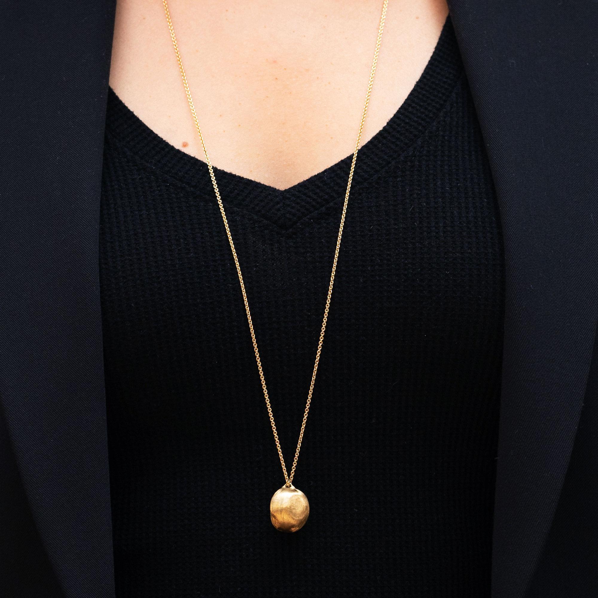 A signed Marco Bicego pendant, from his renowned Africa collection. A hand florentine finish is bestowed on the Italian 18 karat yellow gold pendant, adding an artful accent to this contemporary Italian treasure. Like wearing a piece of fine art,