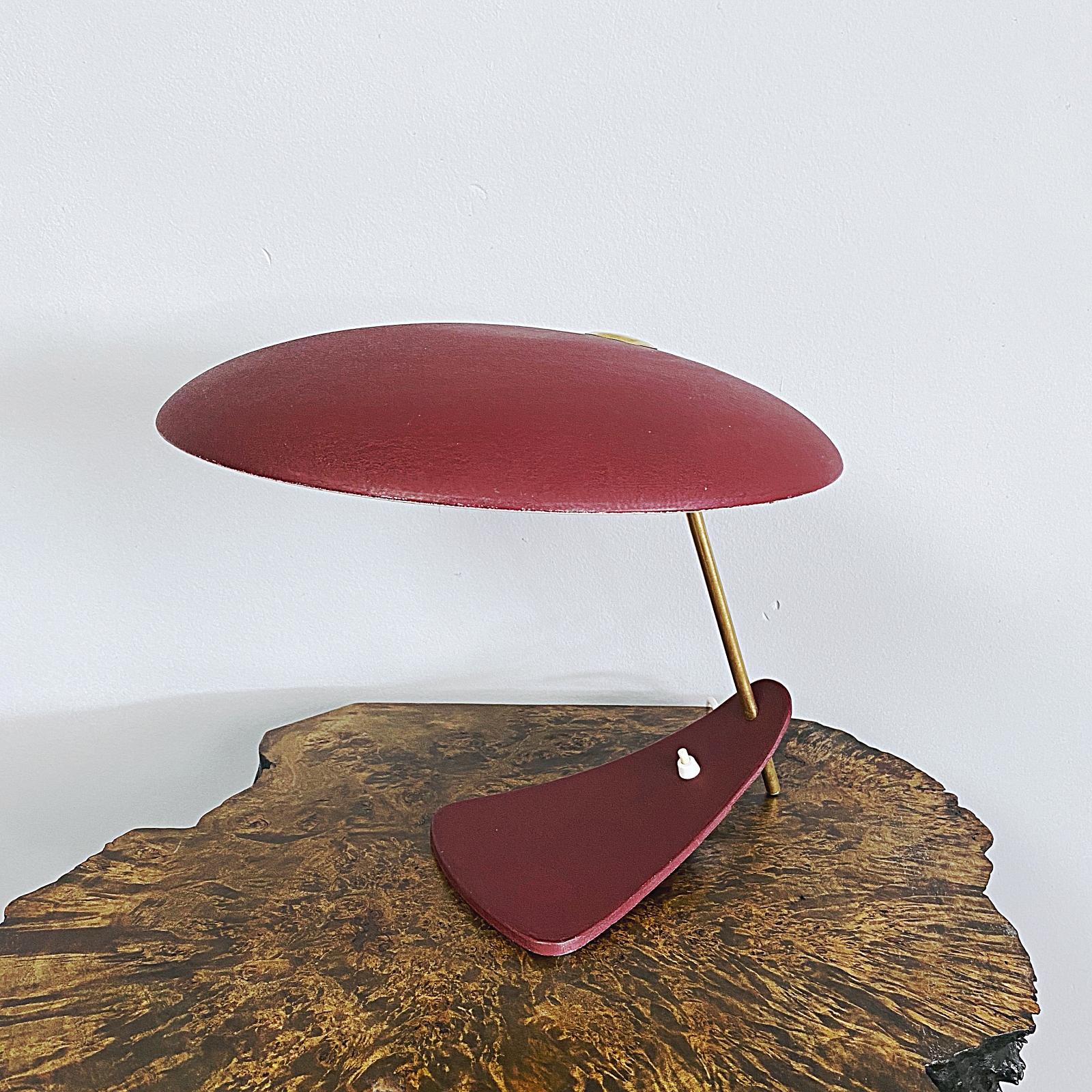 Iconic midcentury desk lamp in bordeaux red wrinkle paint with brass details. Minimalistic design from the 1950s - big round shade with cast iron beak-shaped base. The shade provides a smooth large-area light. Nice patina without bumps or dents.