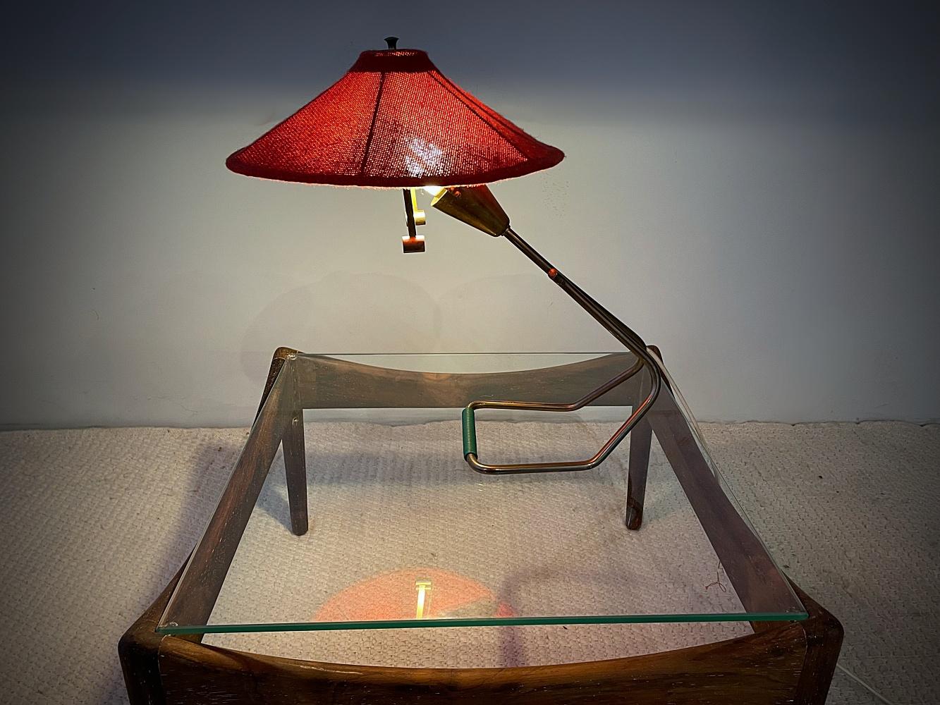 Lampe de bureau iconique du milieu du siècle avec de magnifiques détails en laiton. Design minimaliste des années 1950 - grand abat-jour rond réglable en tissu rouge. L'abat-jour fournit une lumière douce sur une grande surface. Belle patine sans