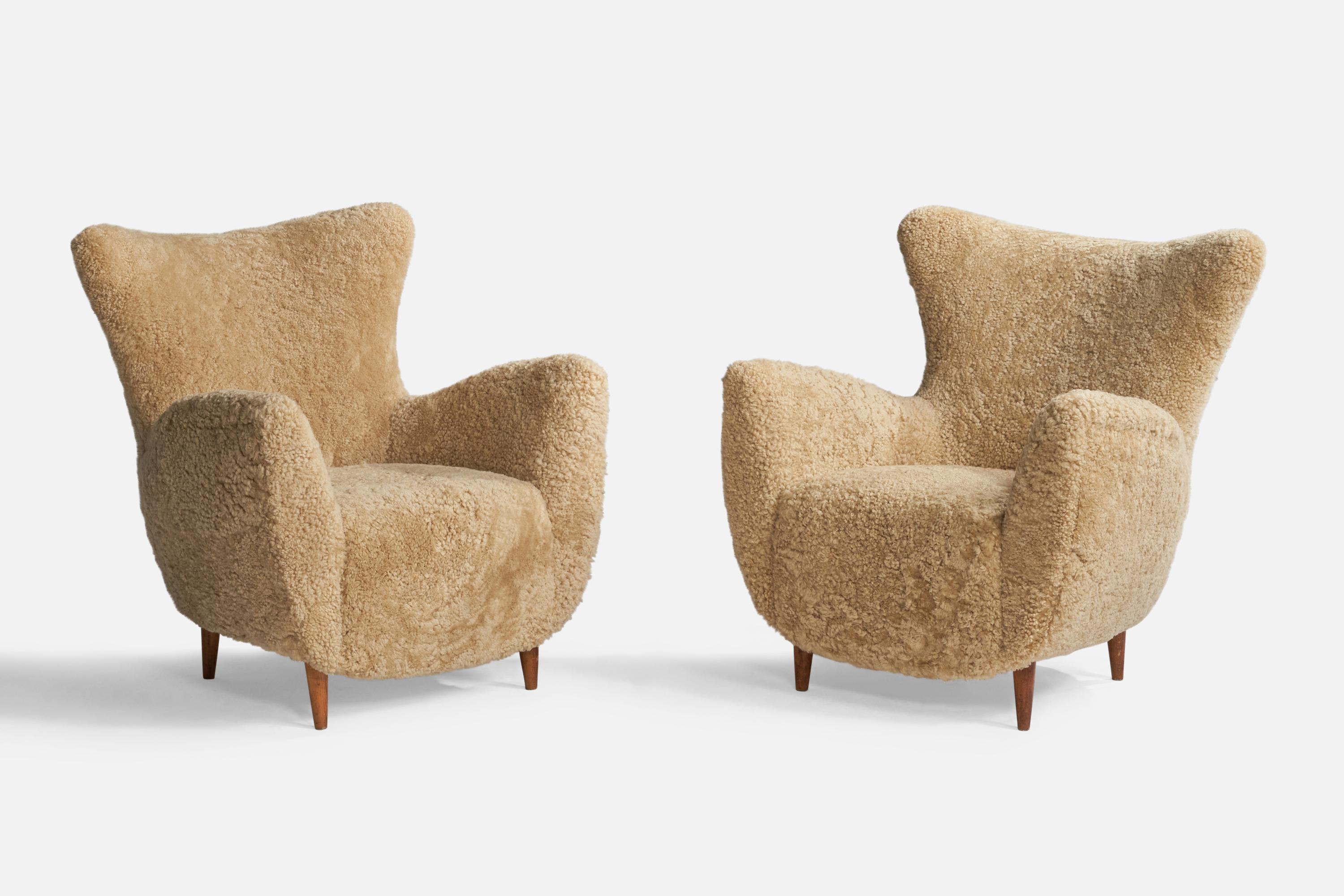 A pair of organic beige shearling and stained wood lounge chairs designed and produced in Italy, 1940s.

Seat height: 16”