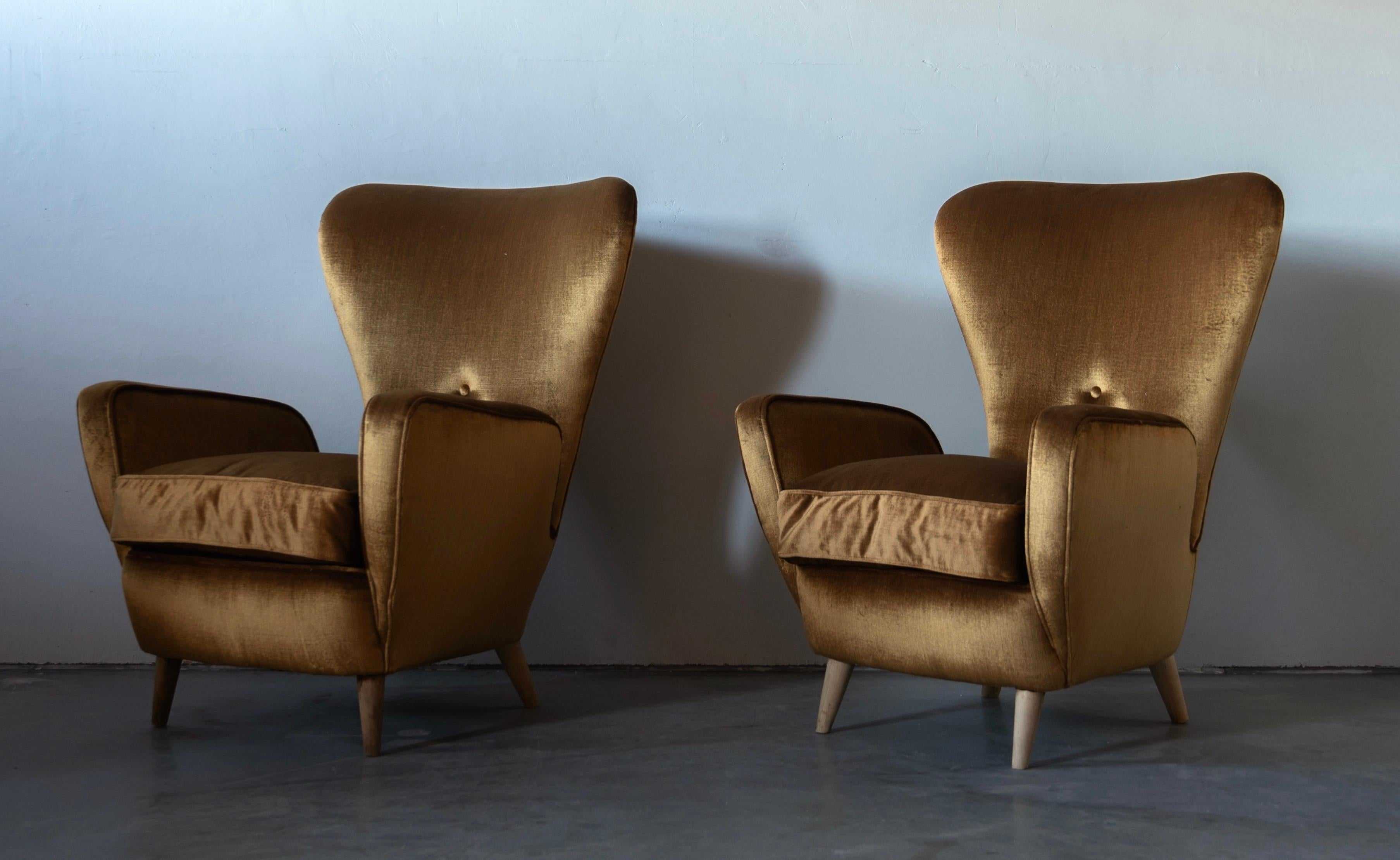 A pair of organic lounge chairs / high-back chairs. Designed and produced in Italy, 1950s. Features an overstuffed form on bleached wooden legs. Vintage fabric. 

Other designers of the period include Guglielmo Veronesi, Federico Munari, Gio