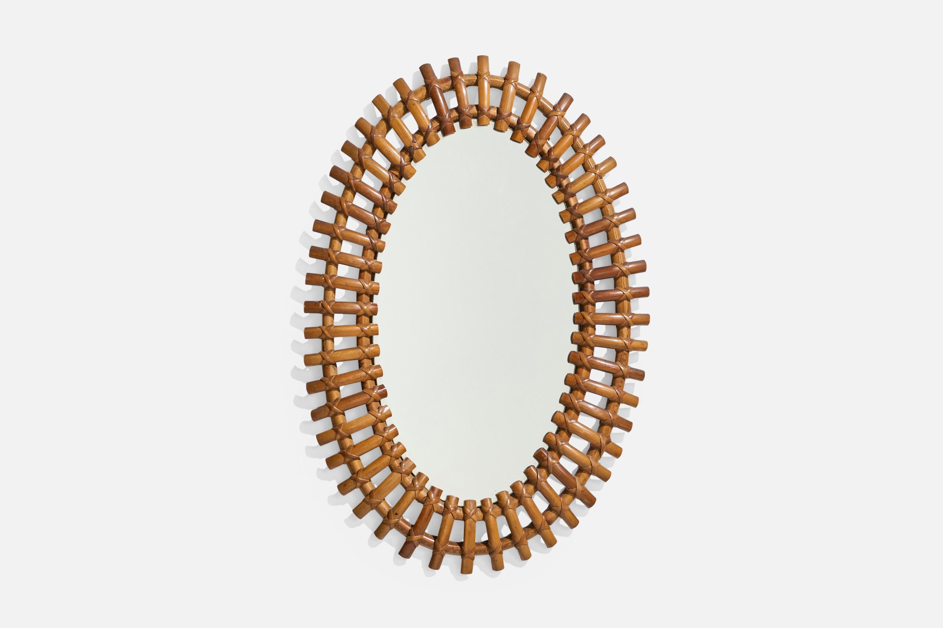 Espejo de pared ovalado, de ratán, diseñado y fabricado por un diseñador italiano, Italia, años 50-60.
 
