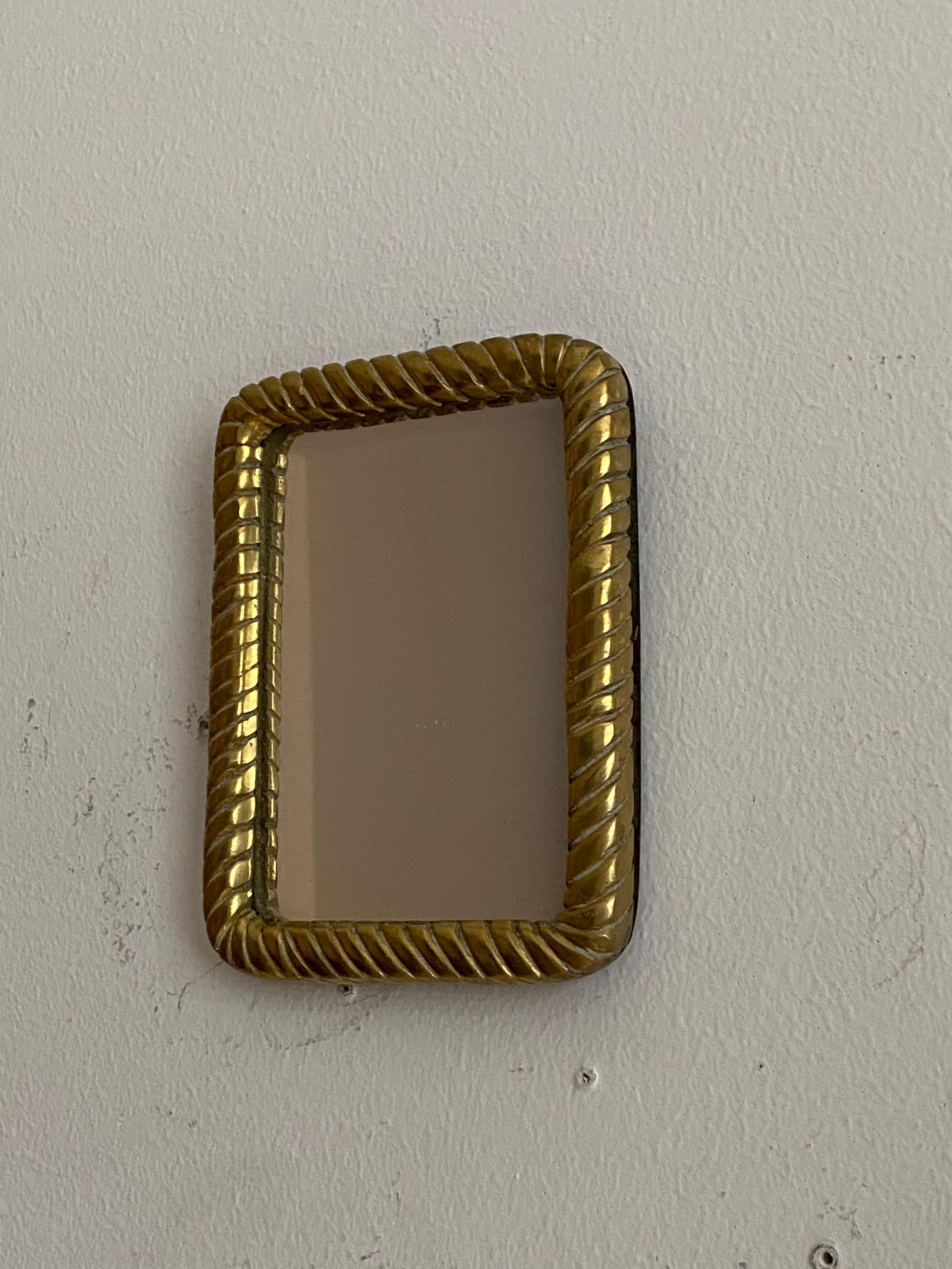 A very small wall mirror, produced in Italy, 1940s-1950s. Cut mirror glass is framed in brass frame.

Other designers of the period include Gio Ponti, Fontana Arte, Paolo Buffa, Franco Albini, and Jean Royere.