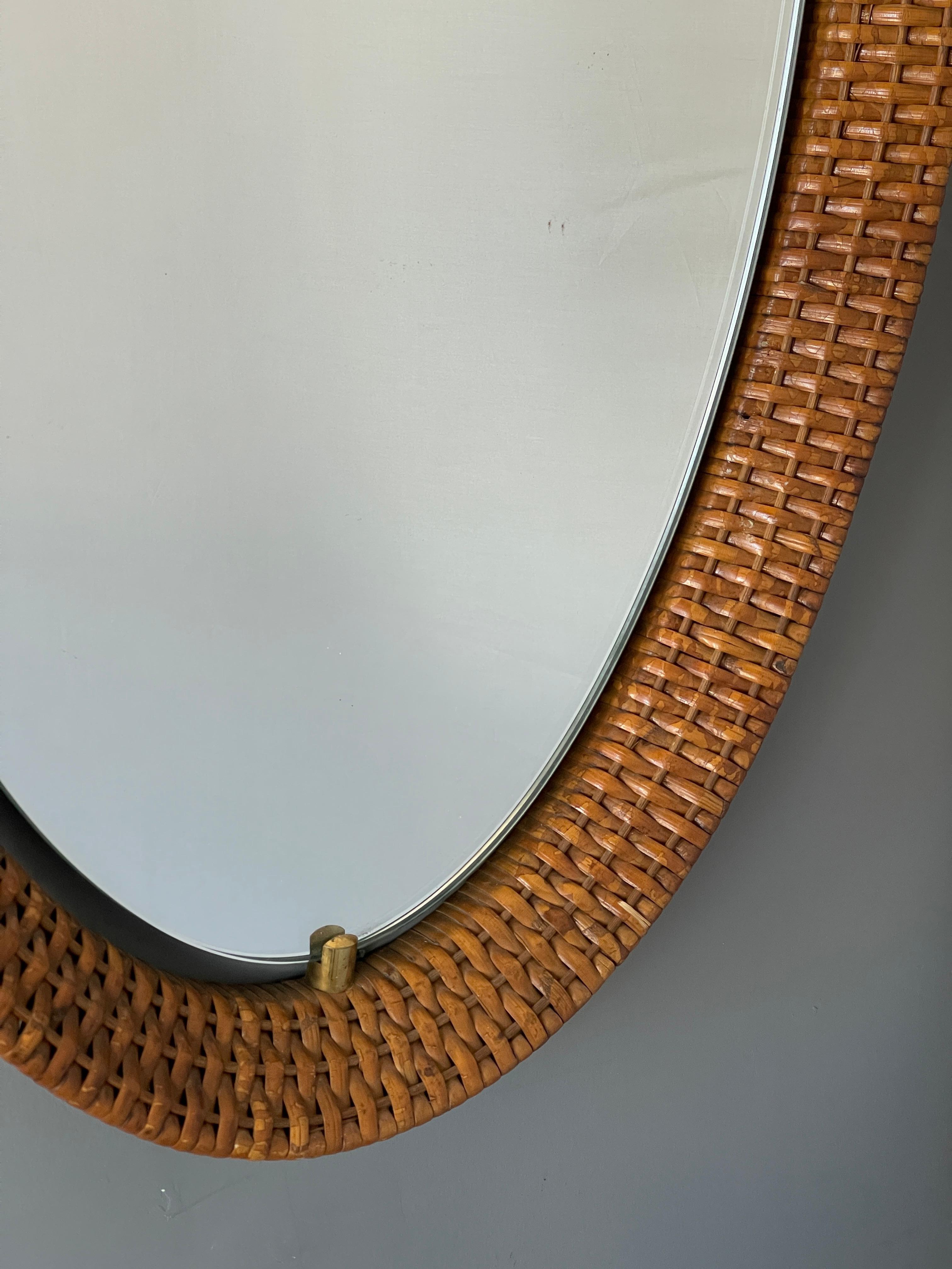 A wall mirror, produced in Italy, 1950s. Cut mirror glass is framed rattan, fixated by brass hardware.

Other designers of the period include Gio Ponti, Fontana Arte, Max Ingrand, Franco Albini, and Josef Frank.
