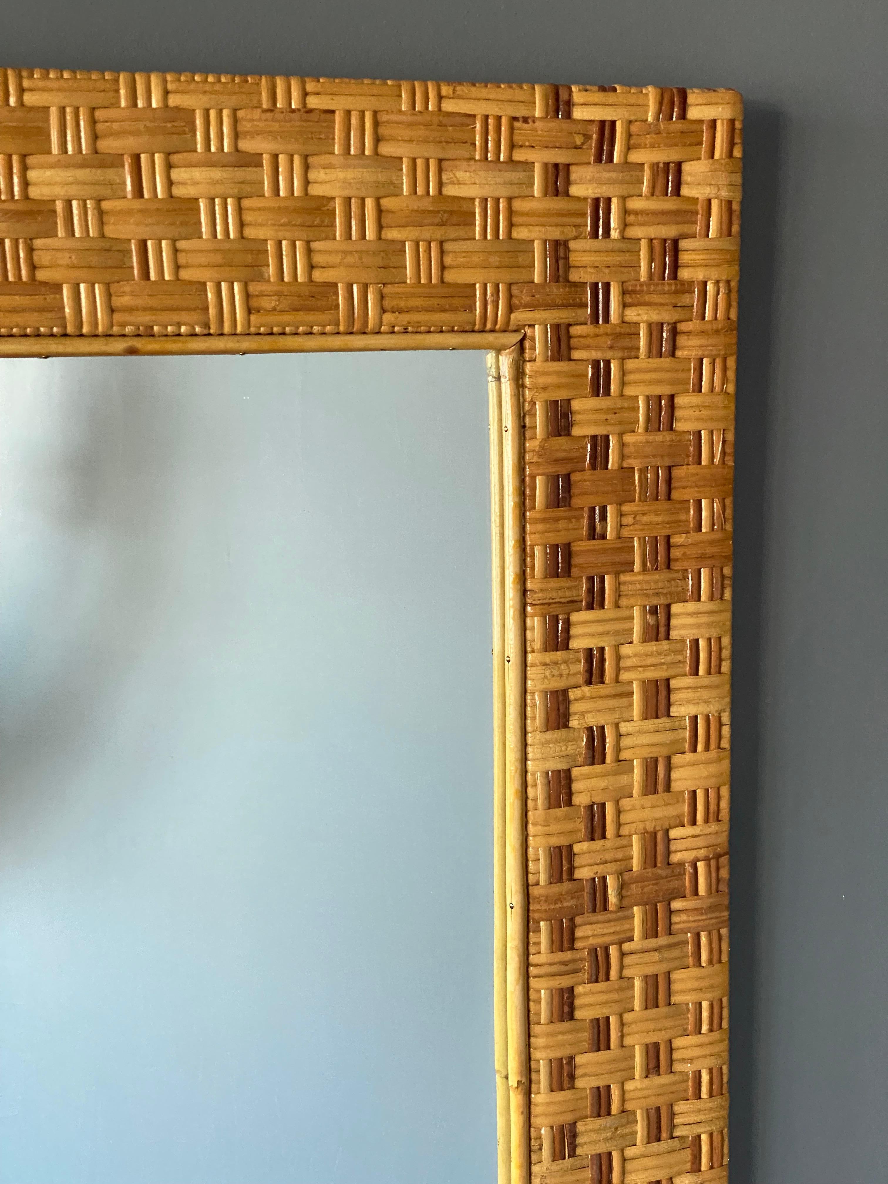 A wall mirror, produced in Italy, 1950s. Cut mirror glass is framed in bamboo and rattan.

